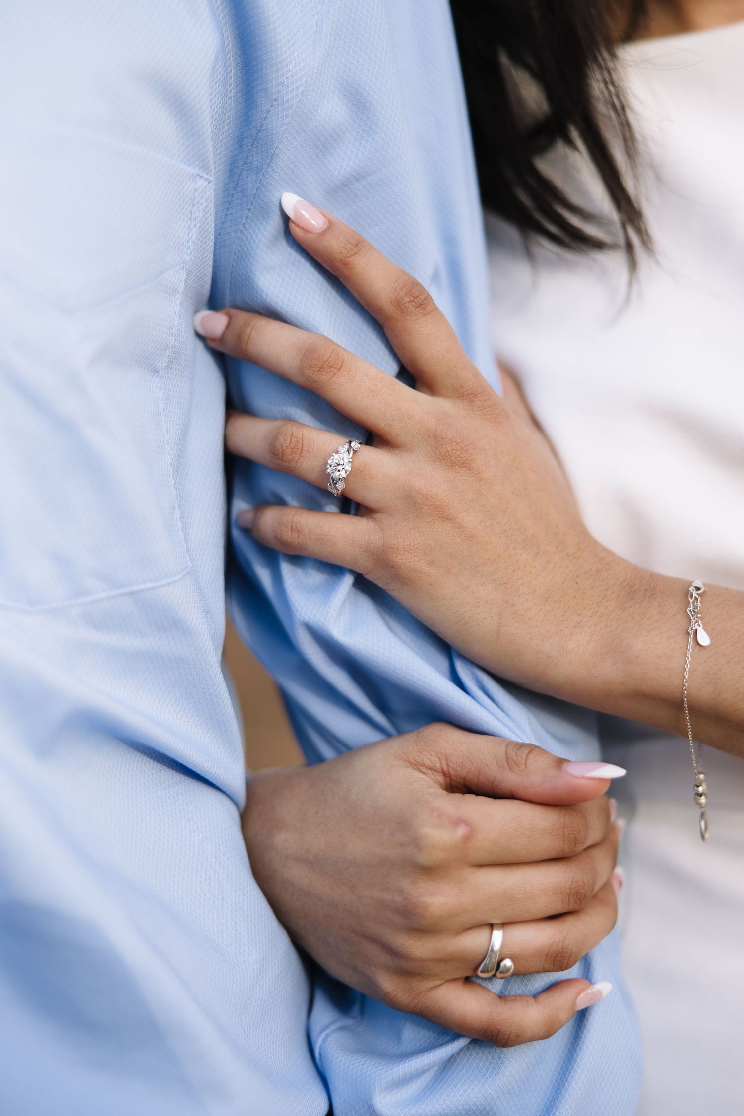 Close-up series of hands wearing an engagement ring against a light blue shirt background.