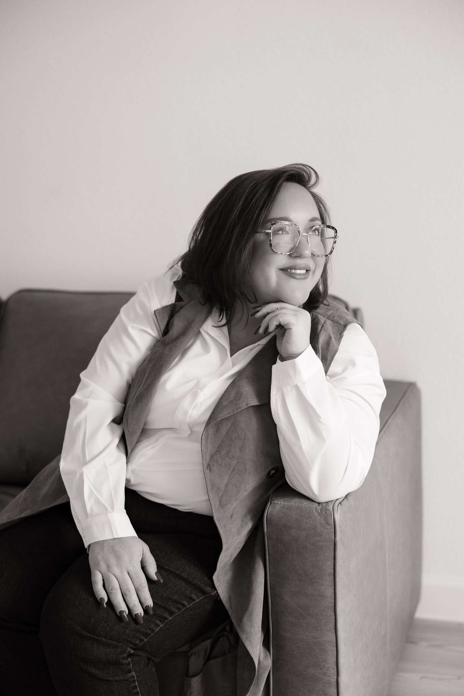 A series of black and white photos showing someone in a white shirt and dark vest sitting and posing on a couch.