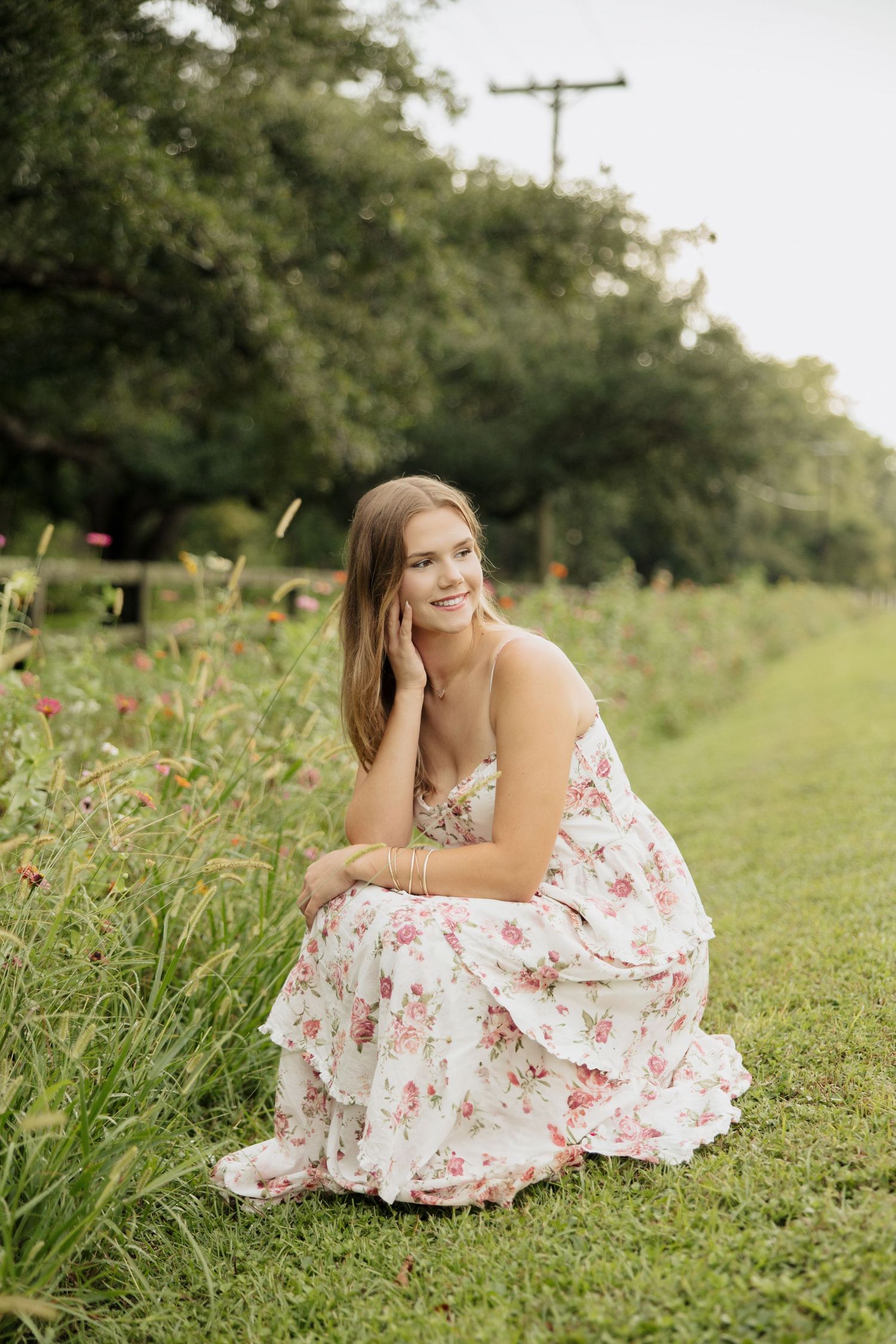 Outdoor portrait session in a flowery field with flowing white and pink dress.