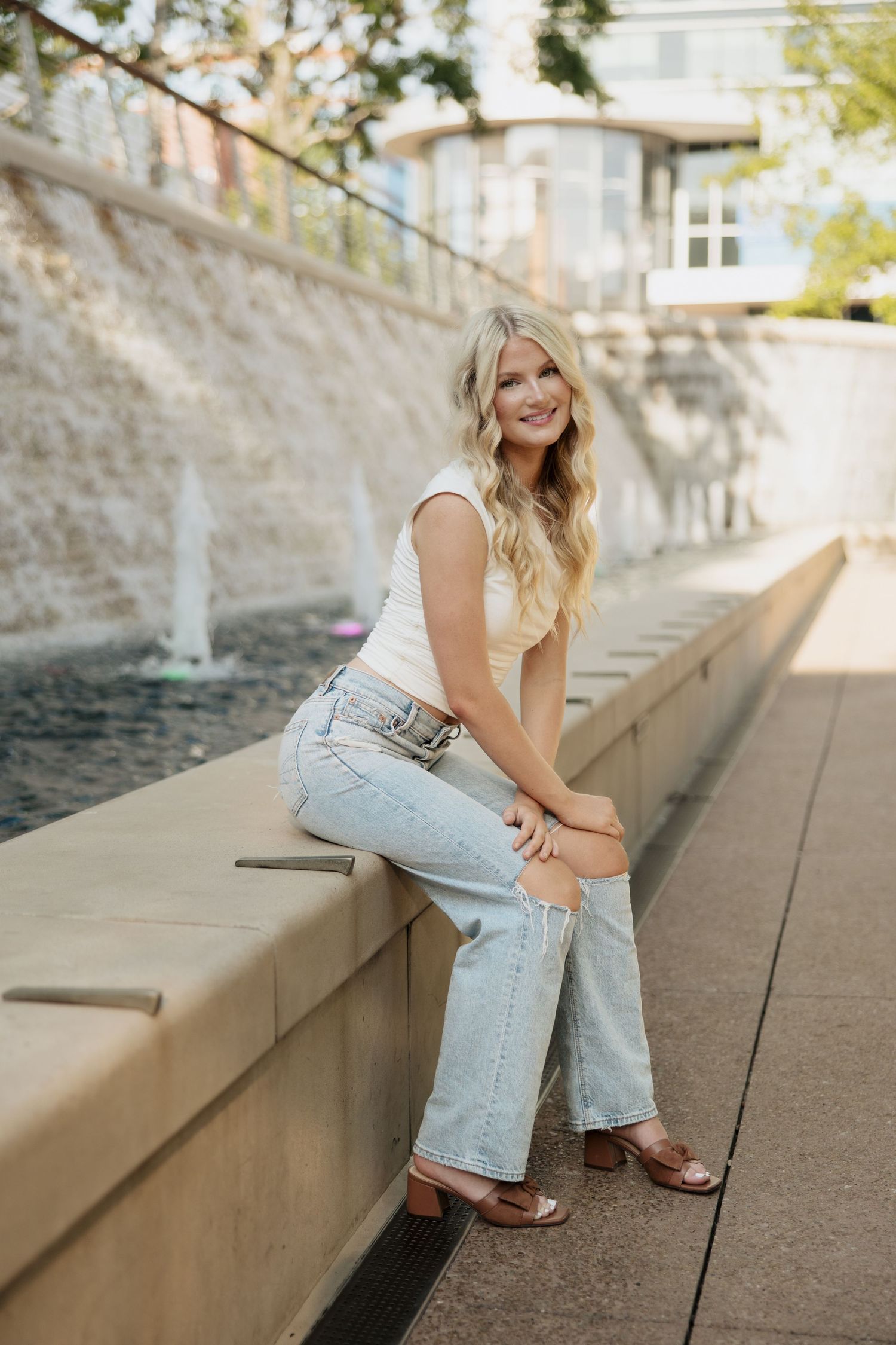 Casual outdoor photoshoot on concrete steps with denim and white outfit styling.