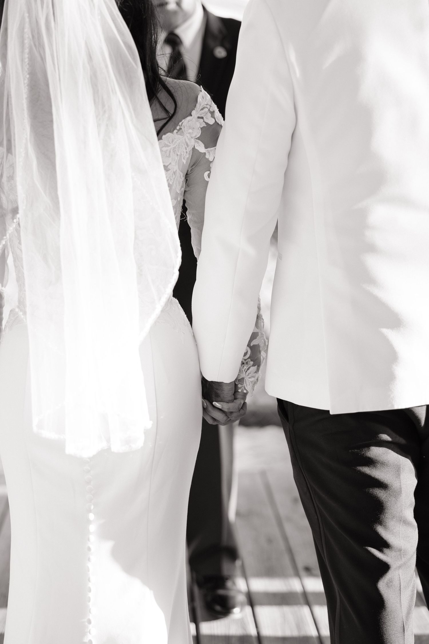 Black and white photograph showing the lower half of people in formal attire at what appears to be a wedding ceremony.
