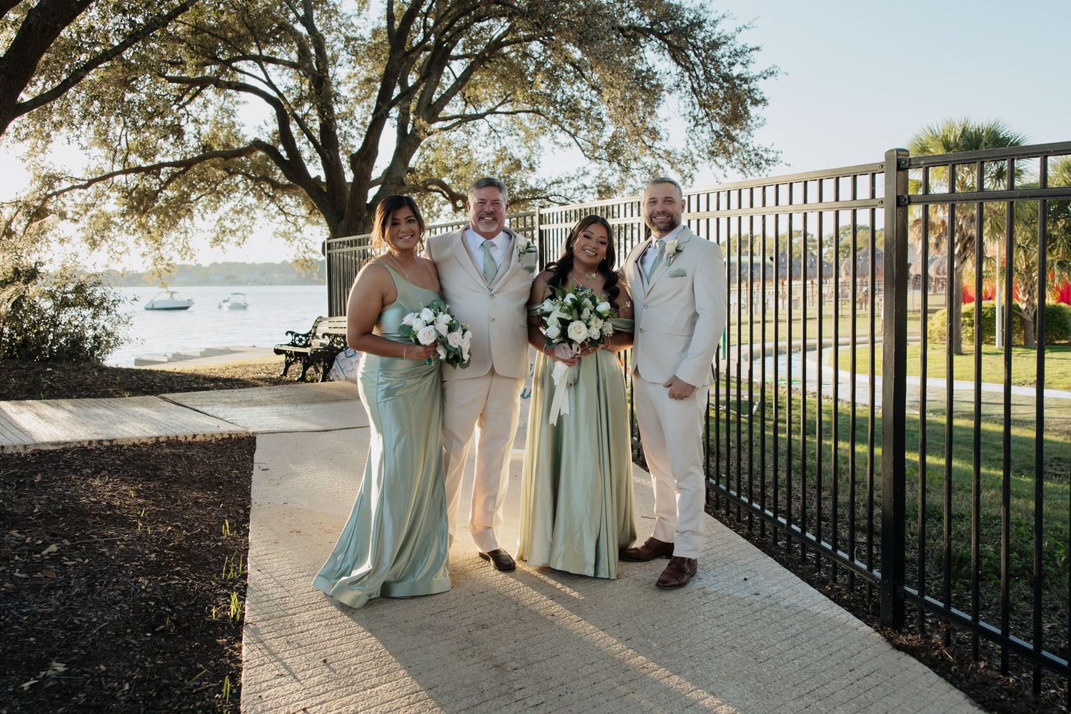 Wedding party stands in elegant poses along a scenic outdoor railing during golden hour.