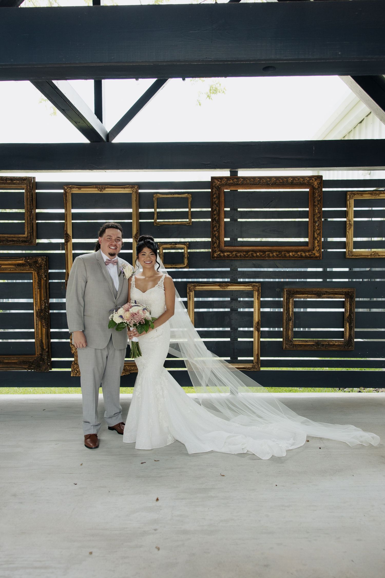 A romantic wedding couple poses against a modern architectural backdrop with horizontal lines and dramatic lighting.