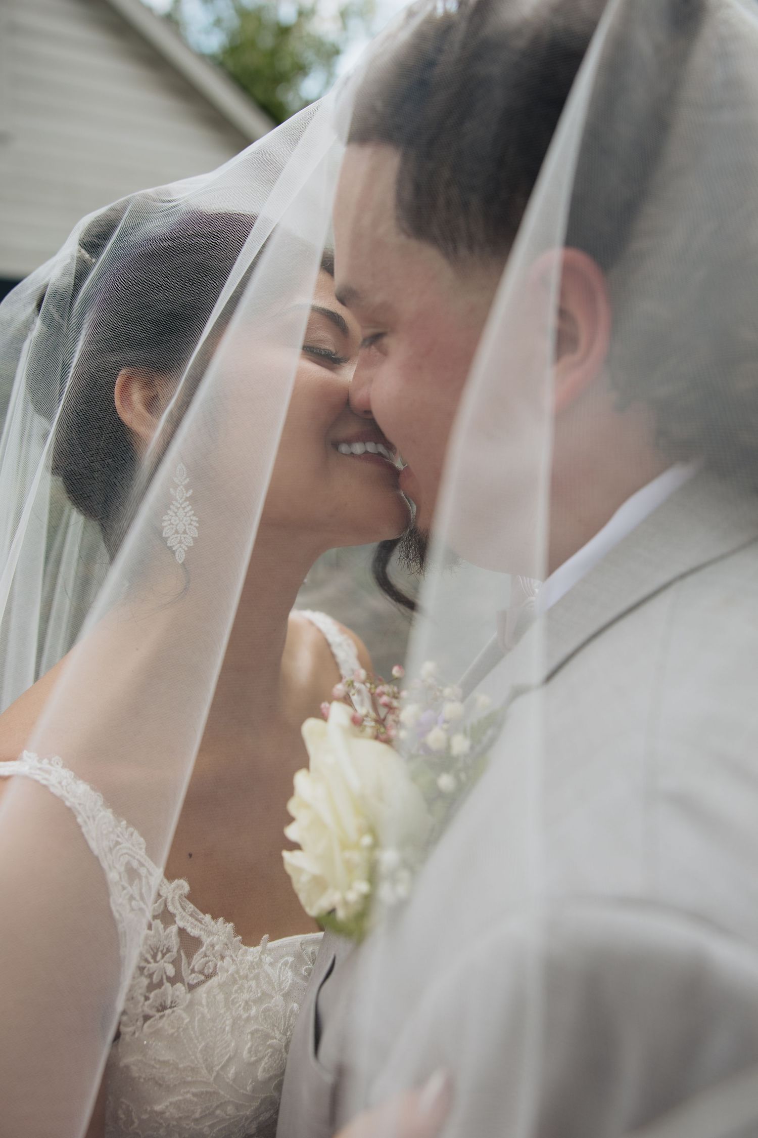 Romantic wedding couple shares intimate moments under a delicate white veil.