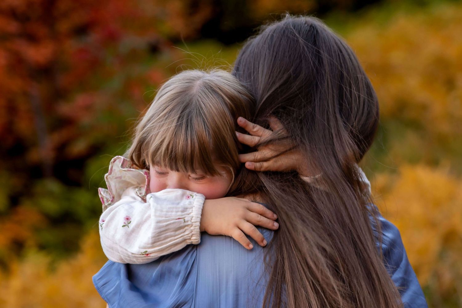 A tender embrace captured against autumn foliage with warm fall colors in the background.