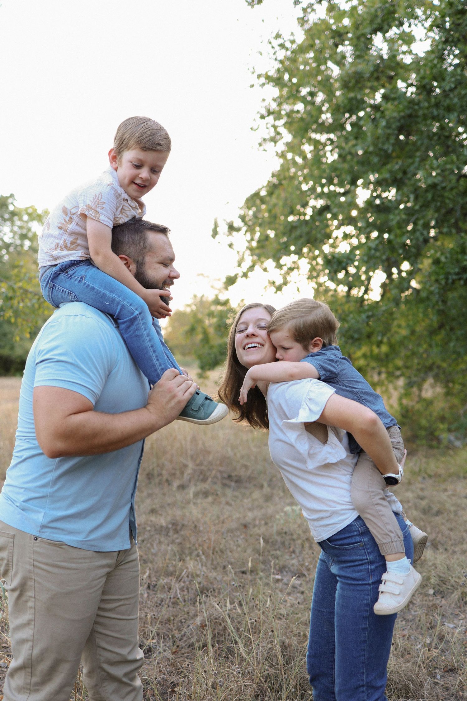Happy family enjoying playful outdoor moments together in a natural setting during golden hour.