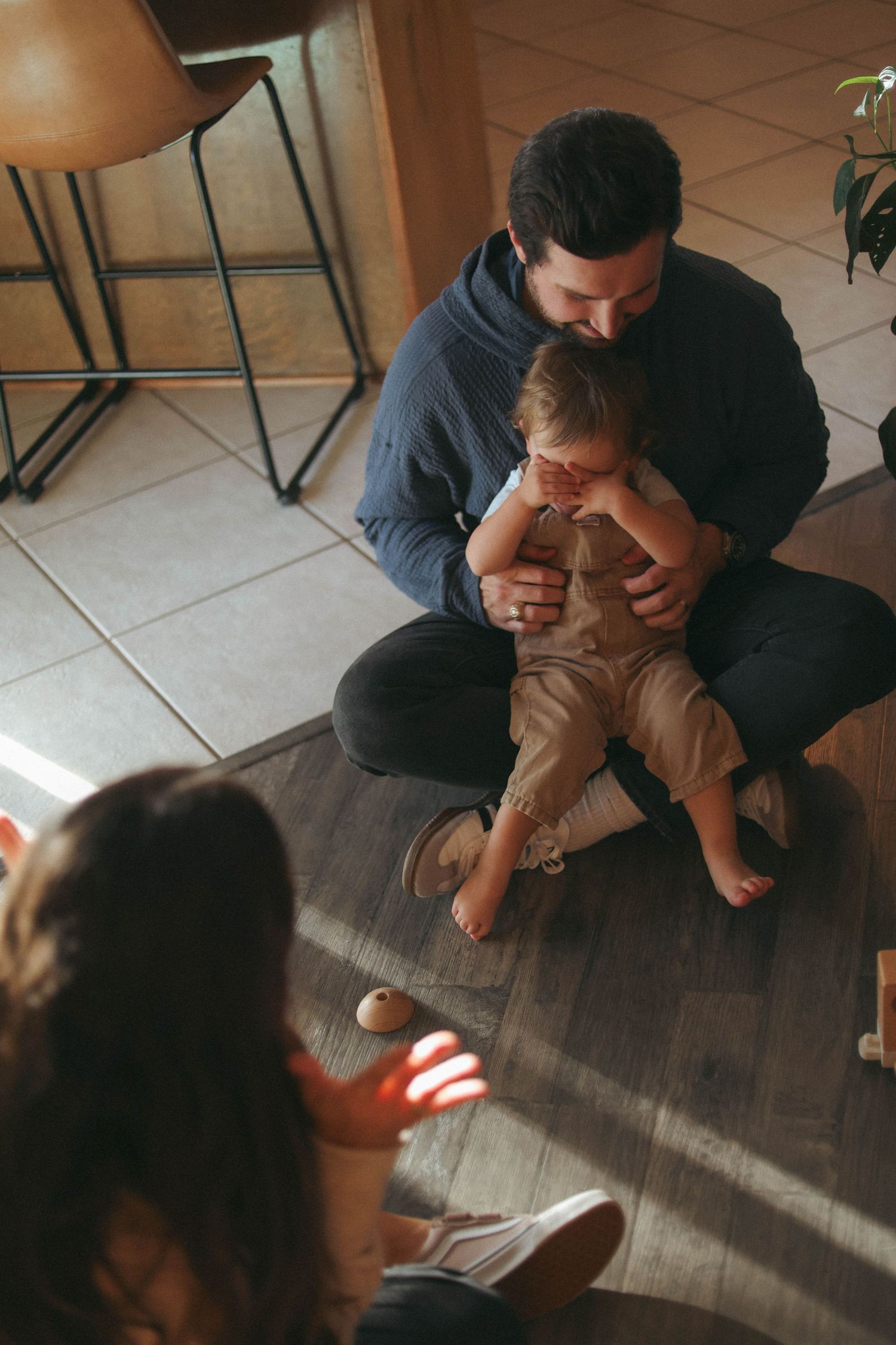 Intimate family lifestyle photos showing parents playing with infant on floor.