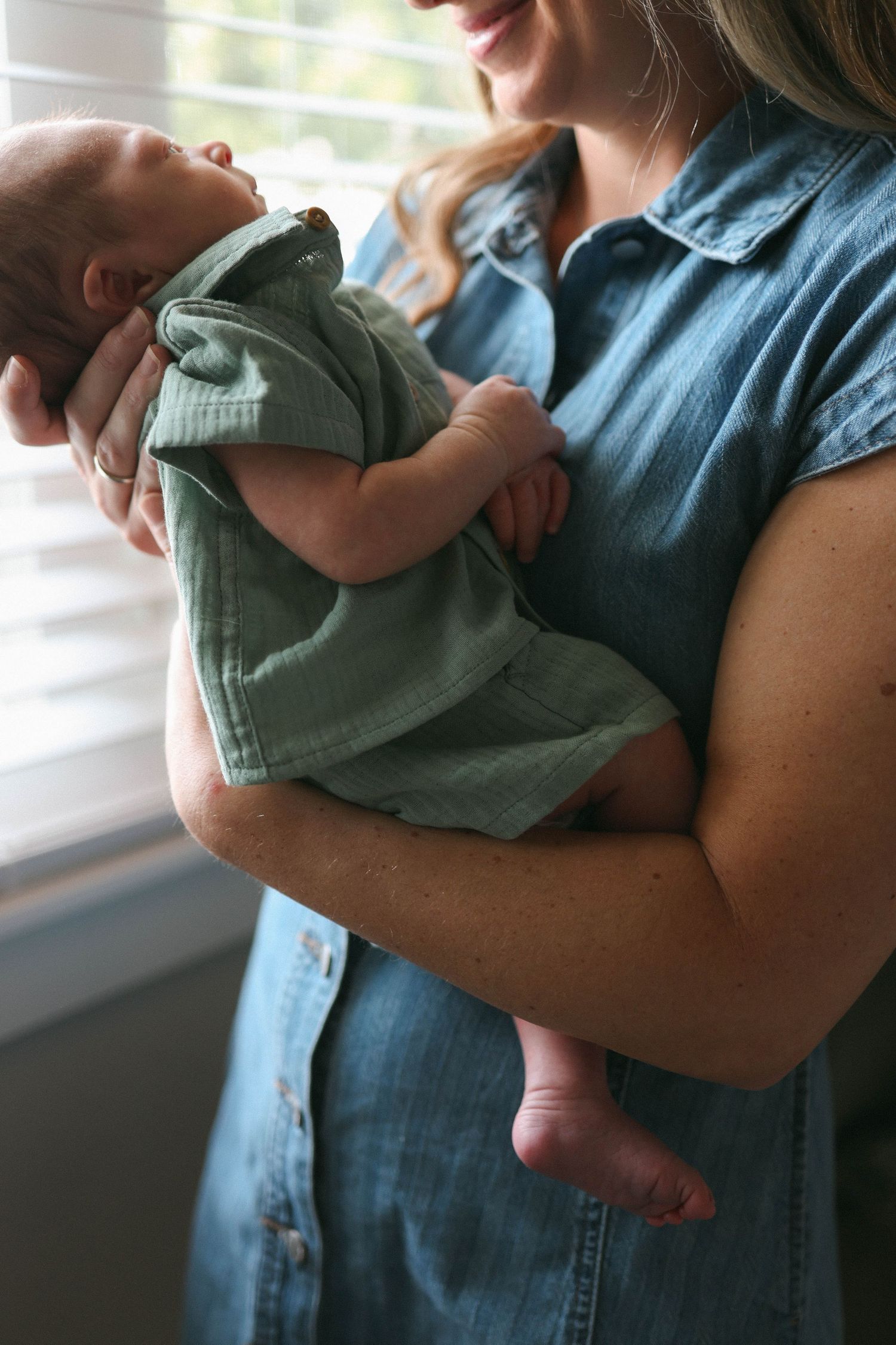 A series of intimate shots showing a mama holding their newborn baby in natural window light.