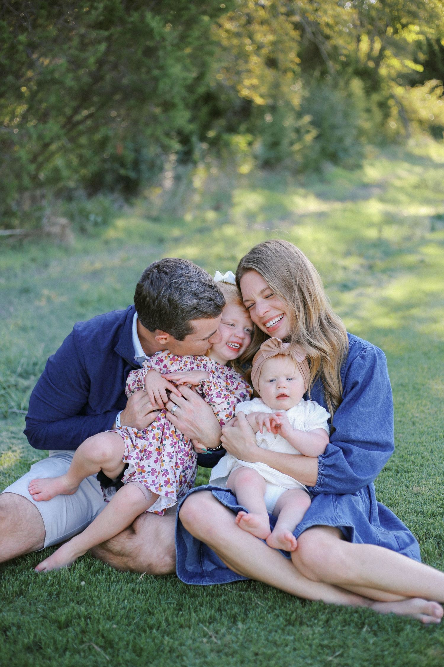 A family shares an intimate moment together while sitting on grass in a park.