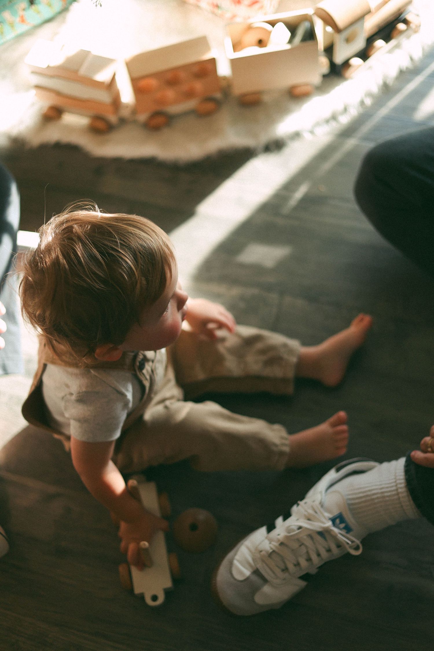 Series of low-angle shots showing small child playing on hardwood floor in sunlight.
