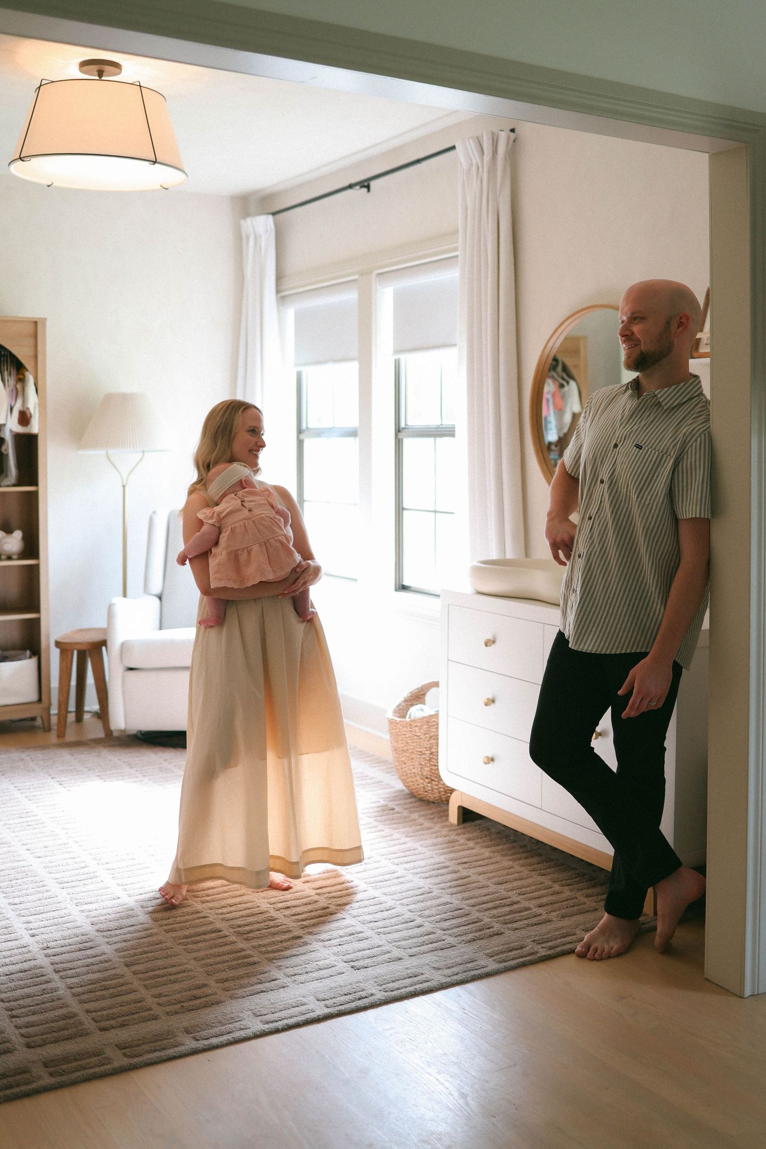 mom and dad holding baby in room during newborn session