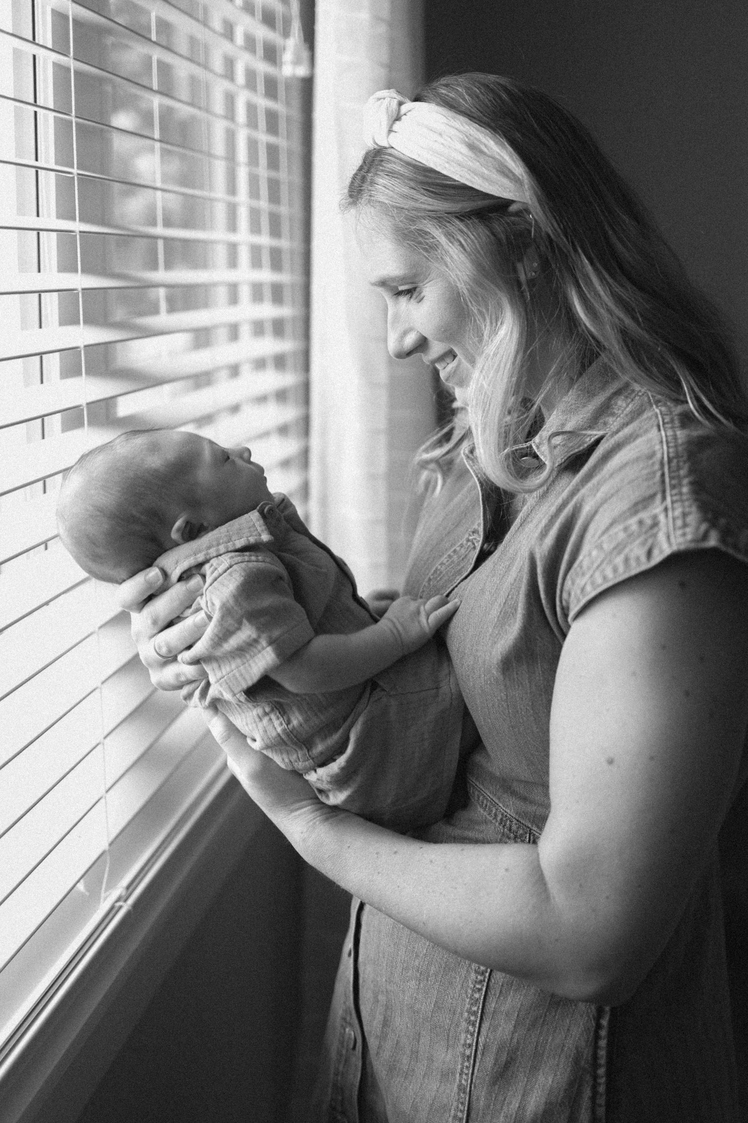 Black and white photos of a tender moment between mom and newborn by a window.