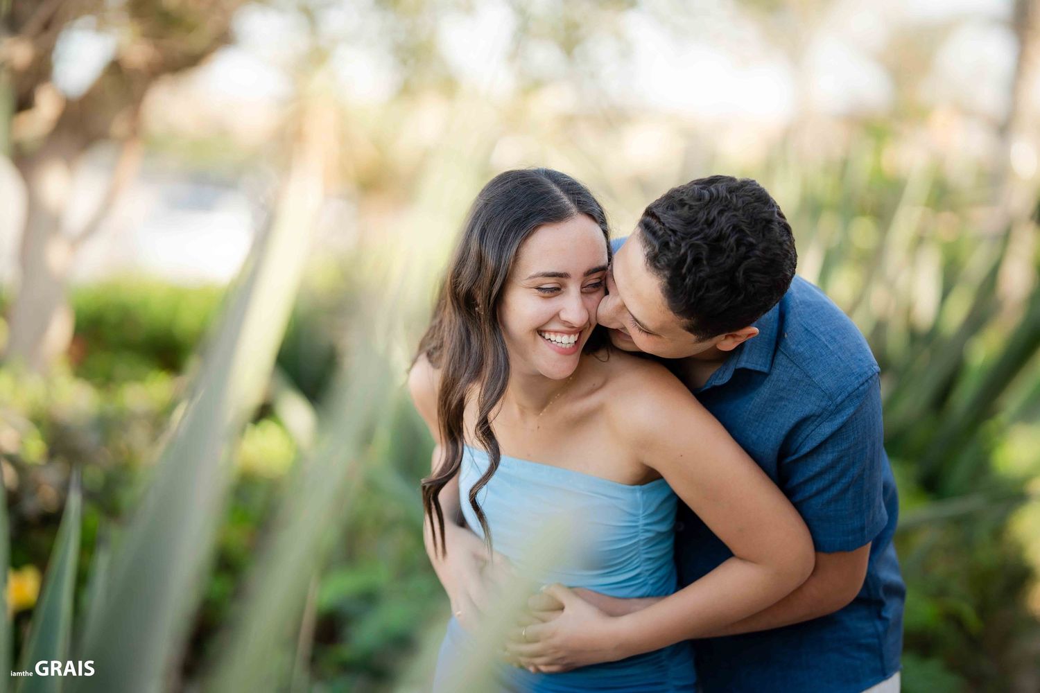A romantic couple shares an intimate moment in a lush garden setting.