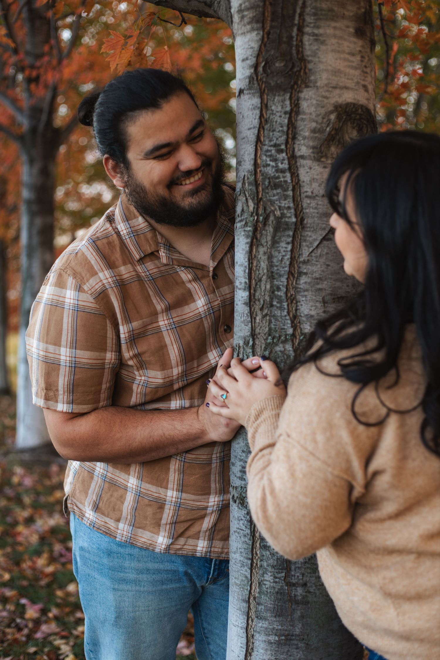 A newly engaged couple shares romantic moments together in a fall setting with bright leaves, taken by Woodbury engagement photographer.