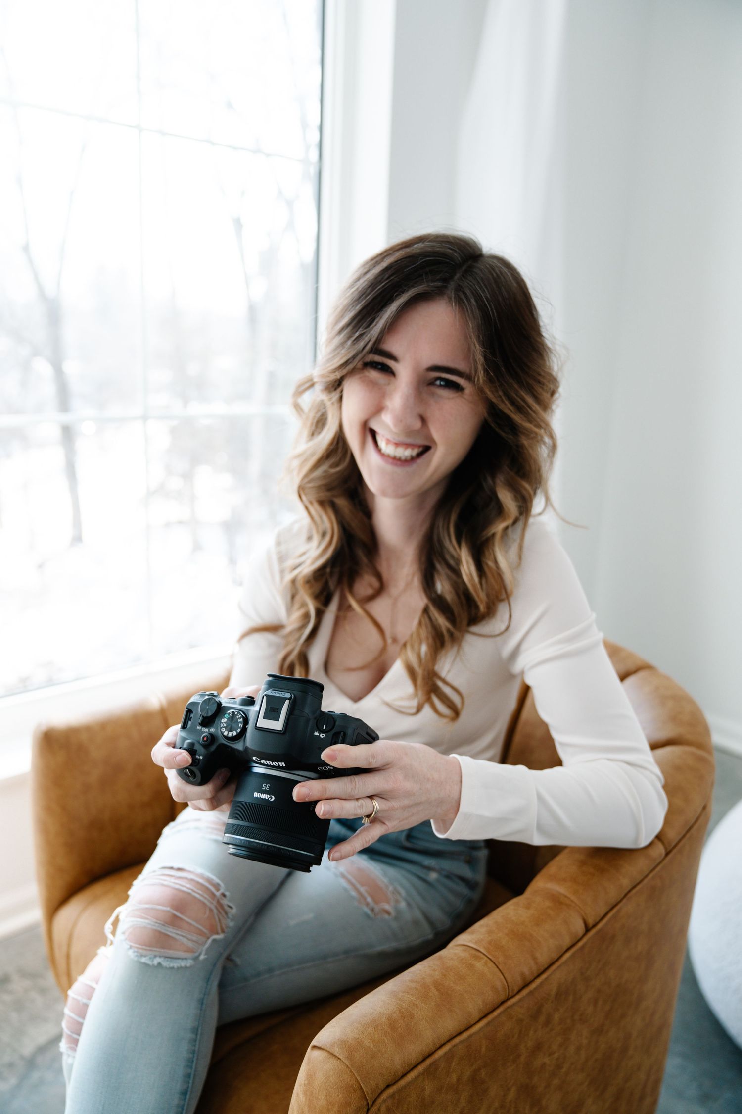 Three connected photos show a Woodbury photographer in a white sweater laughing while reviewing images on a DSLR camera.
