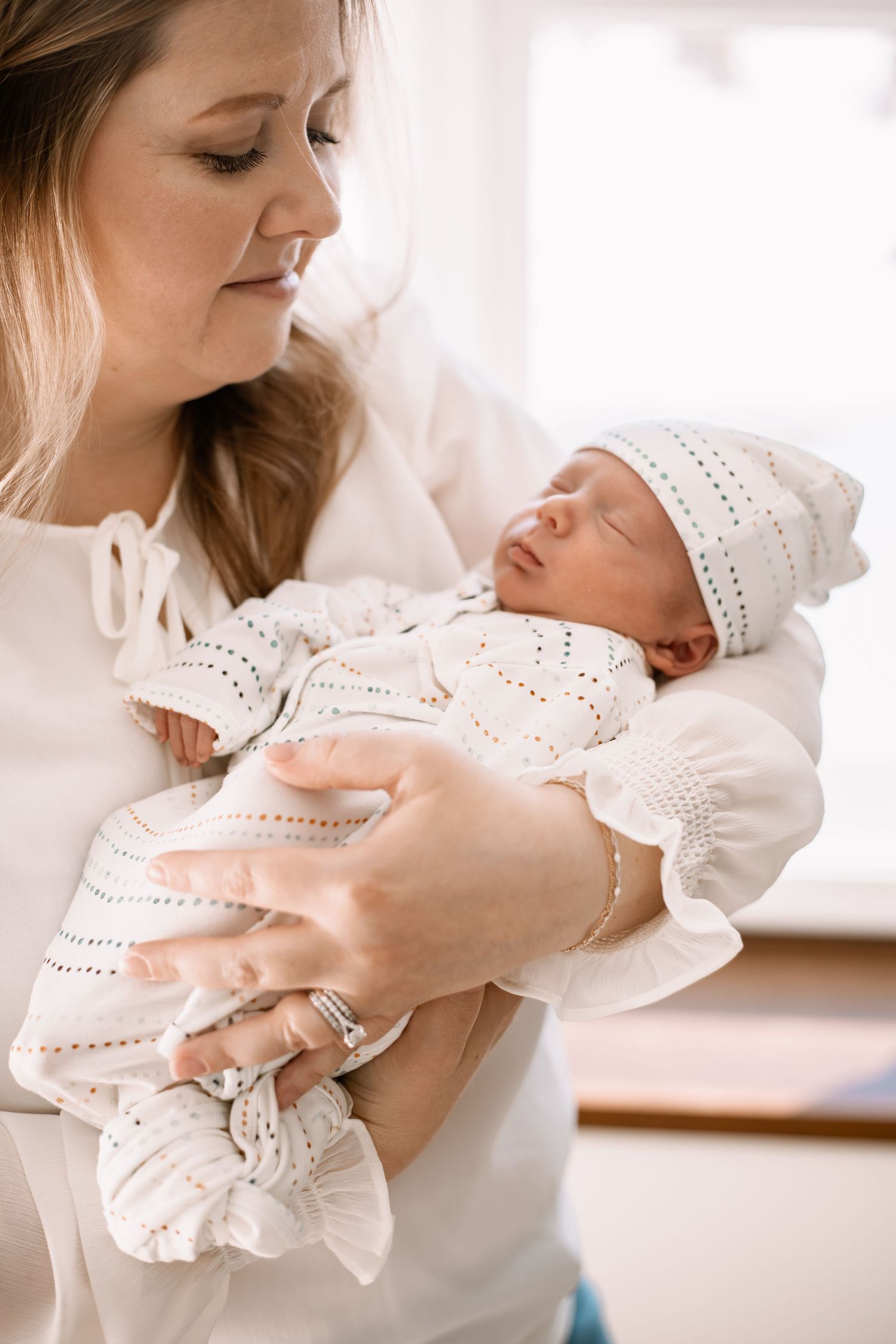A tender moment captured in soft light as a new mother cradles a newborn baby captured by Woodbury newborn photographer.