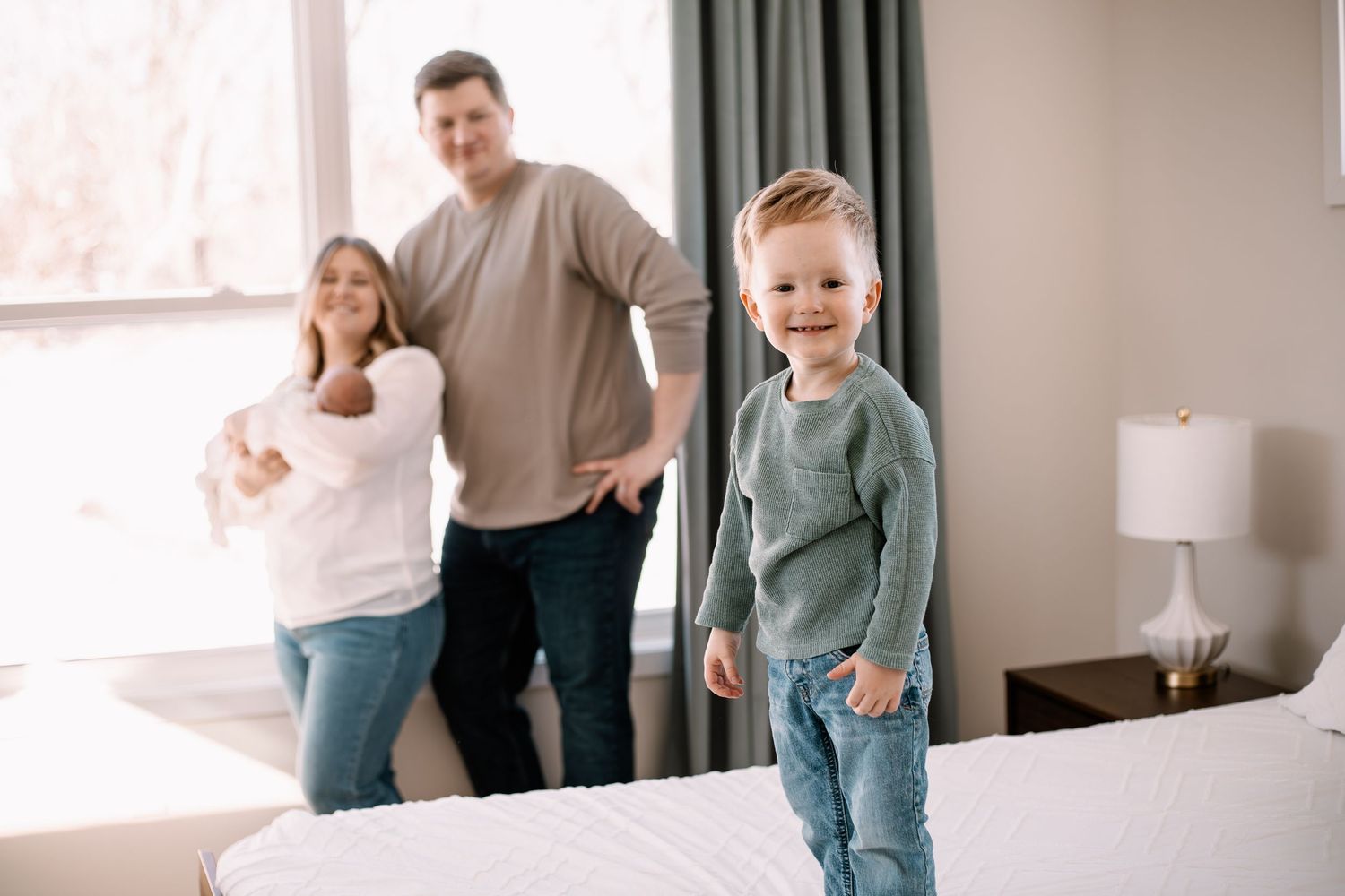 A lifestyle newborn photography session in a bright Lake Elmo home shows candid moments between family members in casual attire.