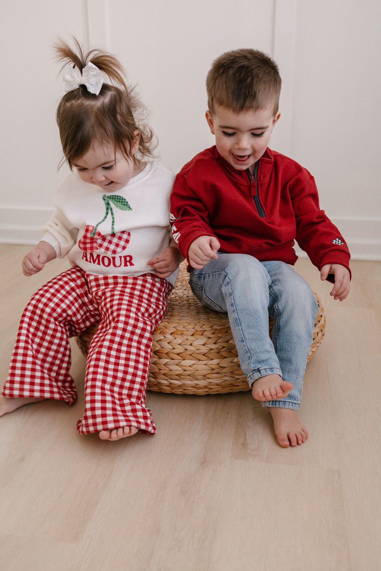Two young children sitting on a woven basket in studio taken by Lakeville family photographer