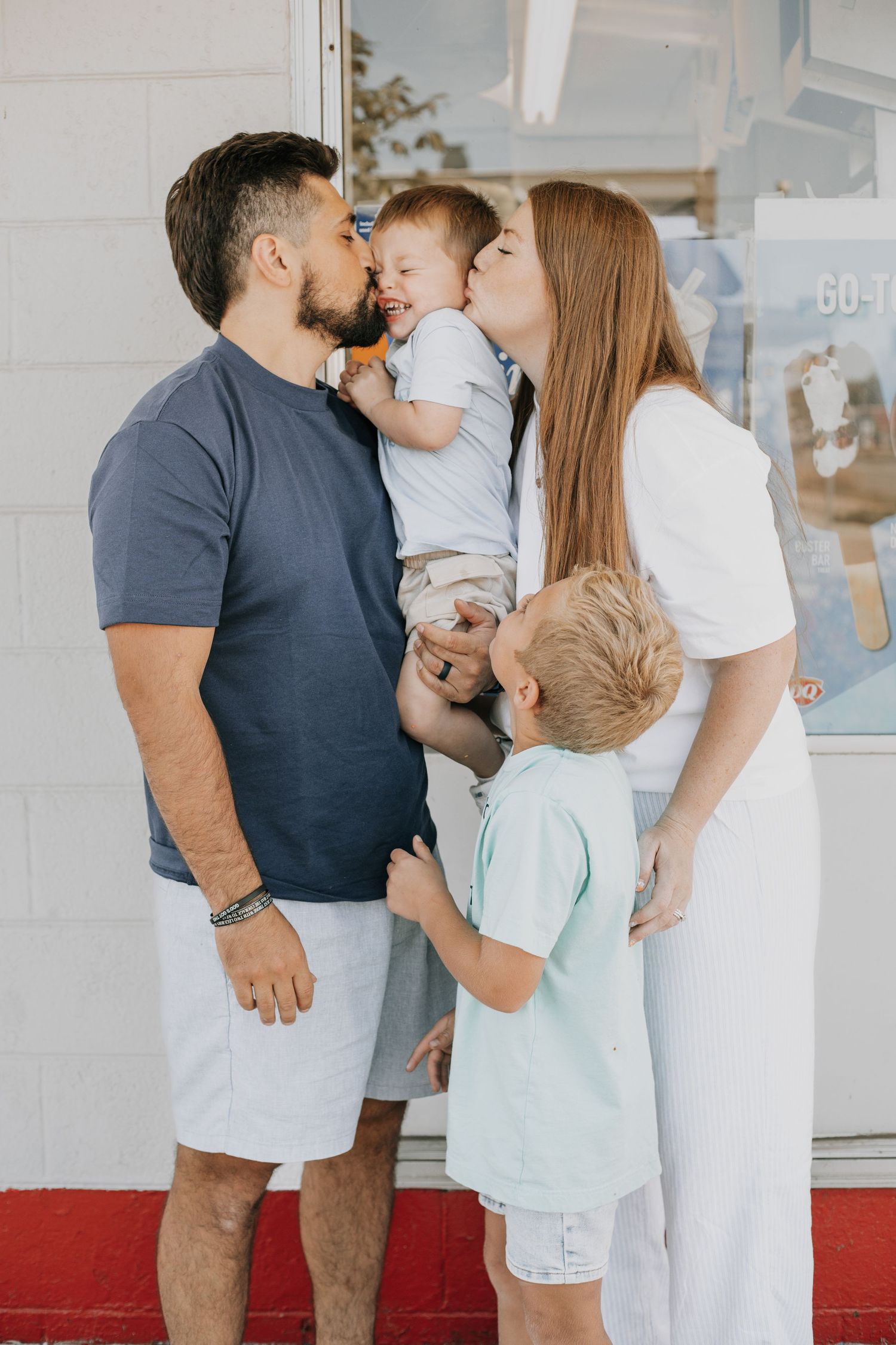 Happy family of four smiles outside ice cream shop in photo session by Woodbury family photographer