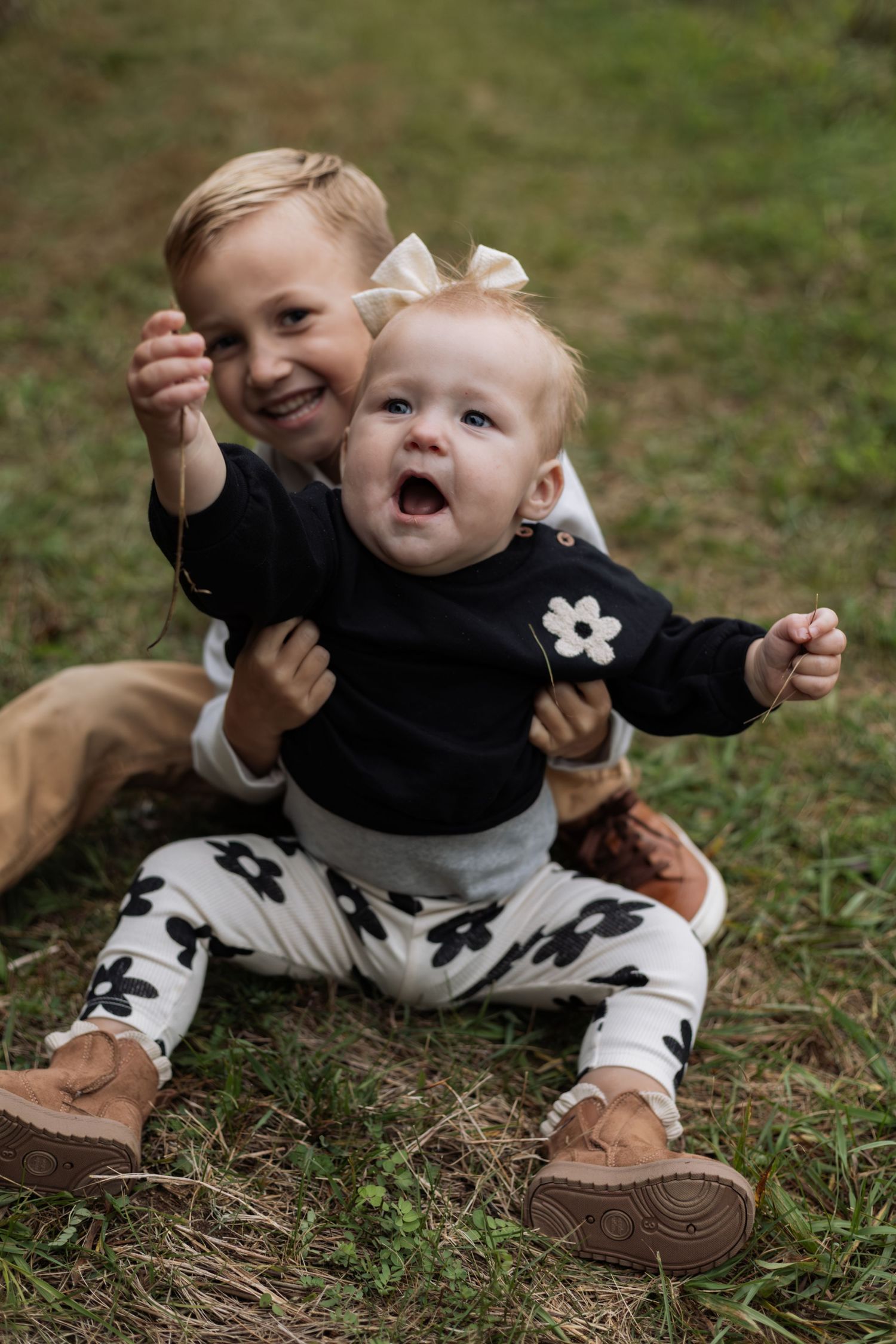Lifestyle family session in Hudson, WI shows two children cuddling in grassy field