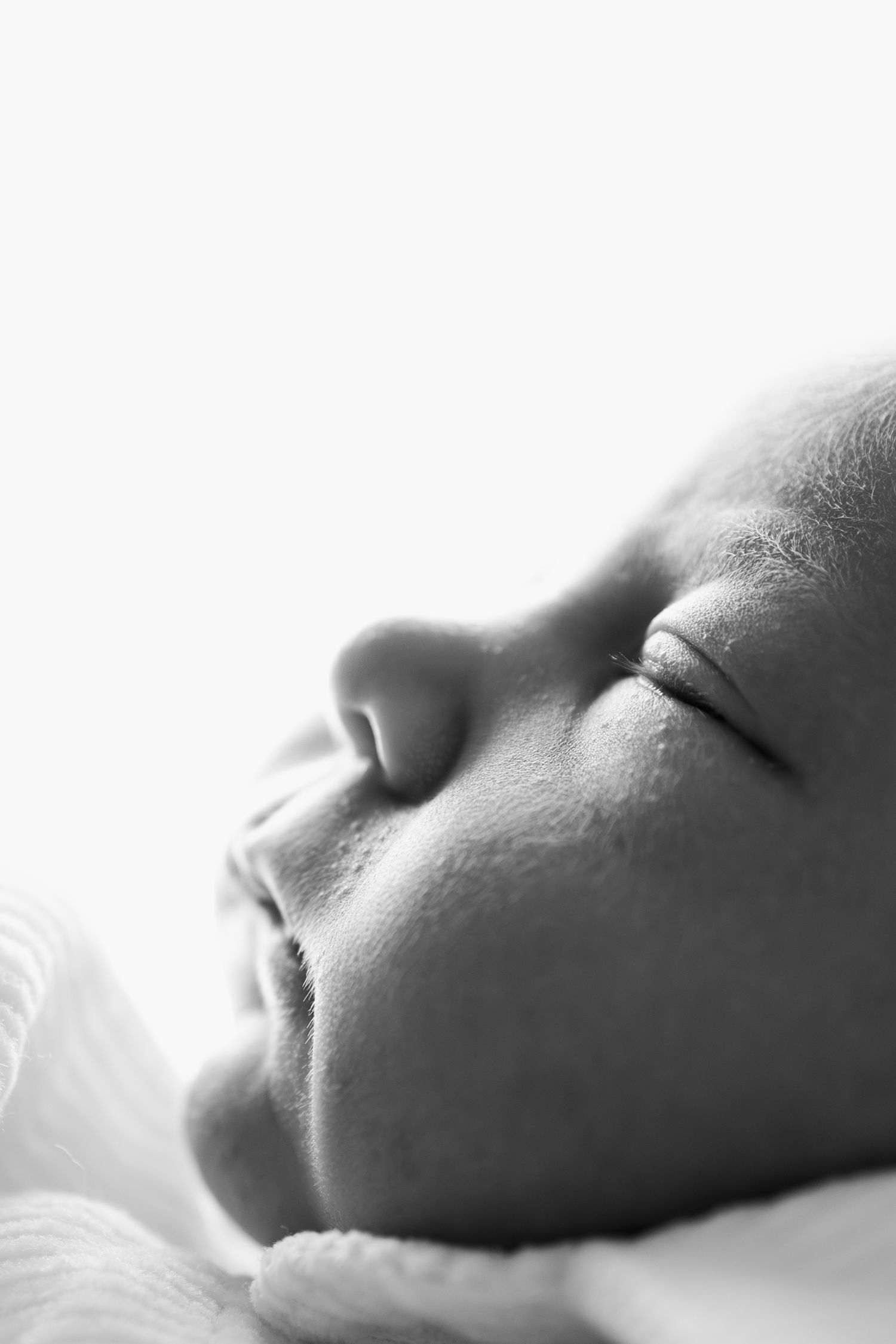 Close-up black and white portrait of a sleeping baby with delicate features and peaceful expression during Lakeville in-home newborn session