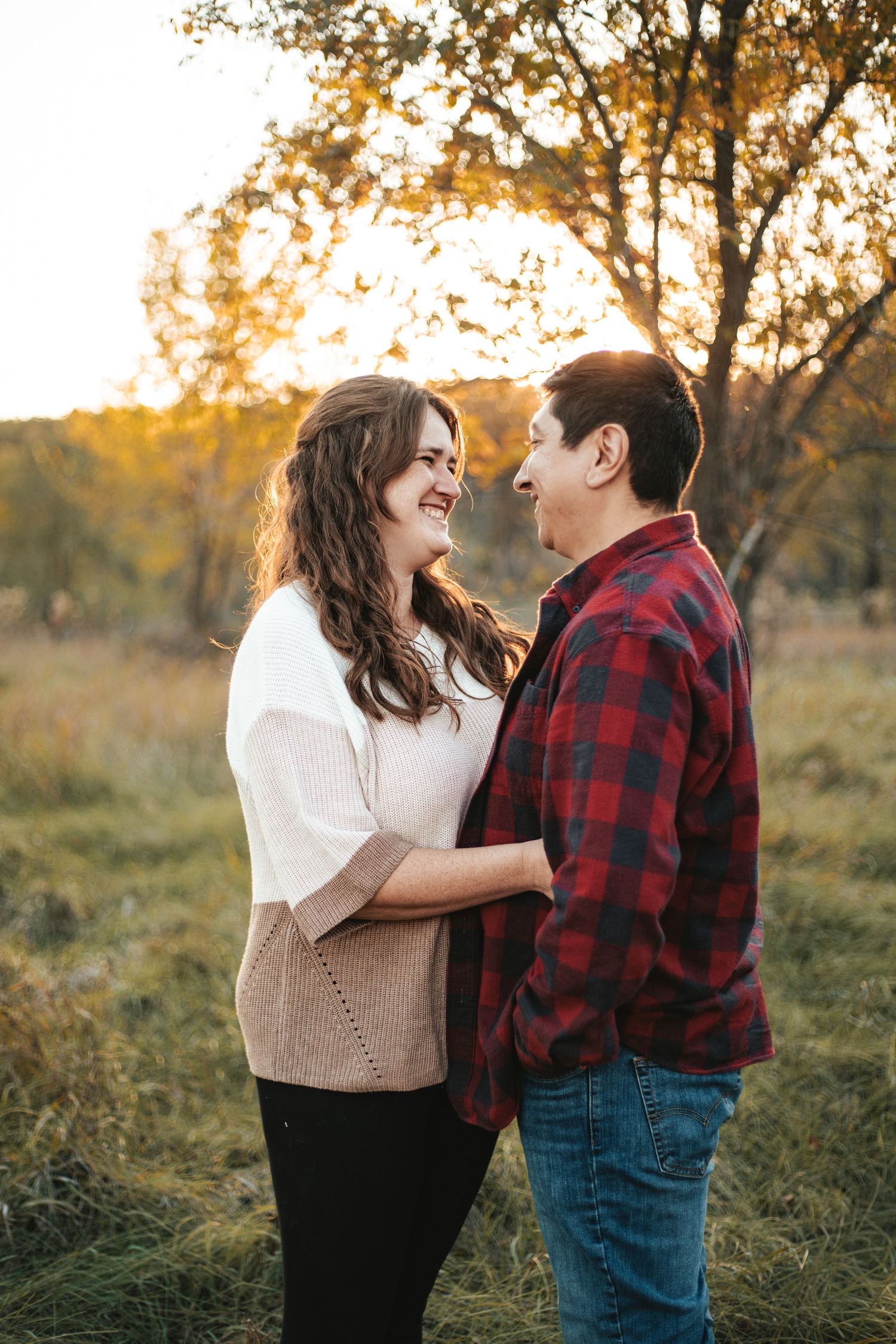 A couple in autumn attire shares a romantic moment at sunset in a golden field of tall grass during Hudson fall mini session.