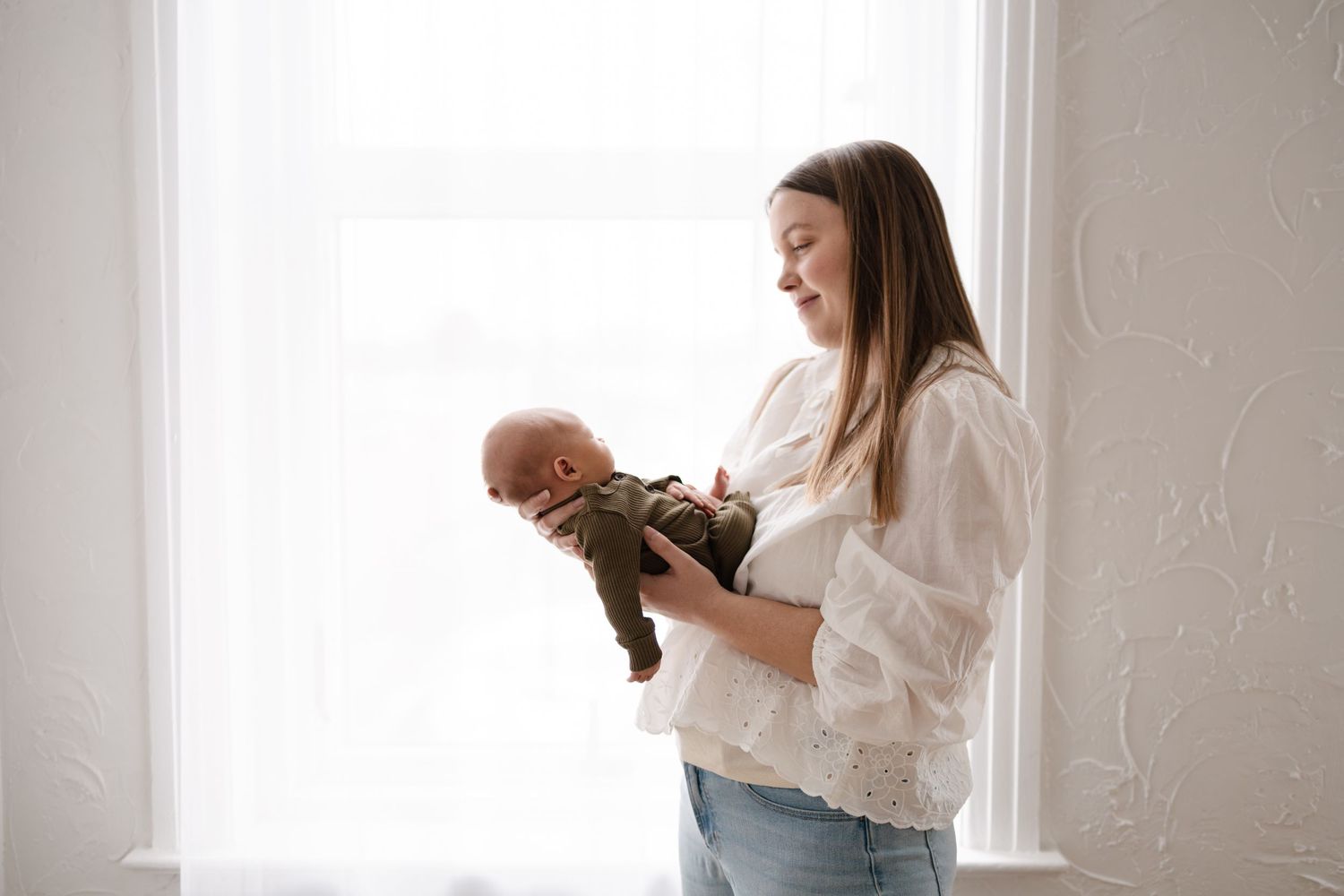 A mother and her baby captured in bright window light by Woodbury family and newborn photographer.