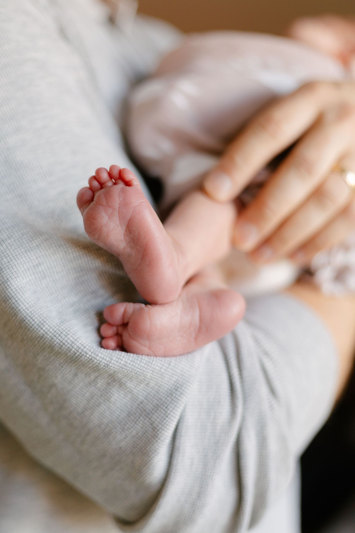 Tiny newborn baby feet resting on soft white fabric showing delicate toes and skin details, taken by Woodbury newborn photographer.