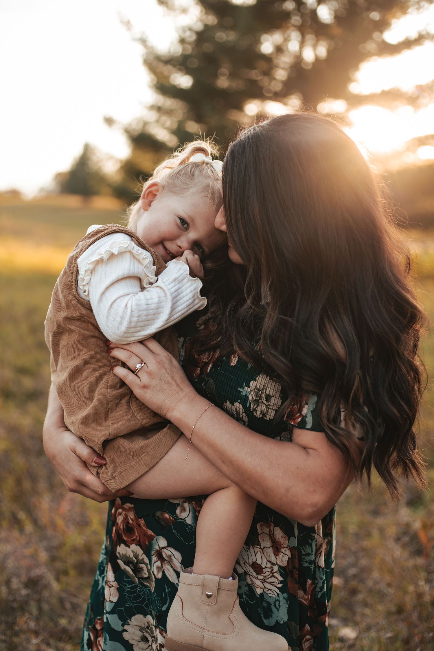 A tender moment between a mother and child is captured in golden sunlight against a natural outdoor setting during Lakeville mini session.