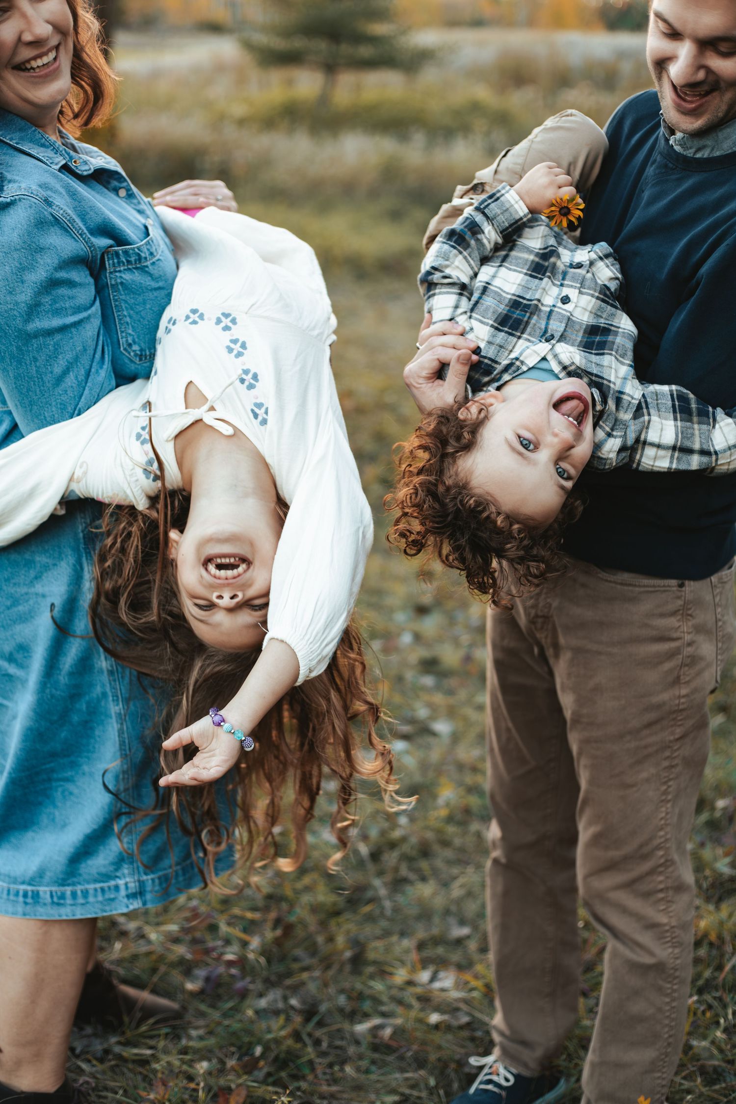 Parents playfully holding children upside down outdoors during fall mini session in Lakeville