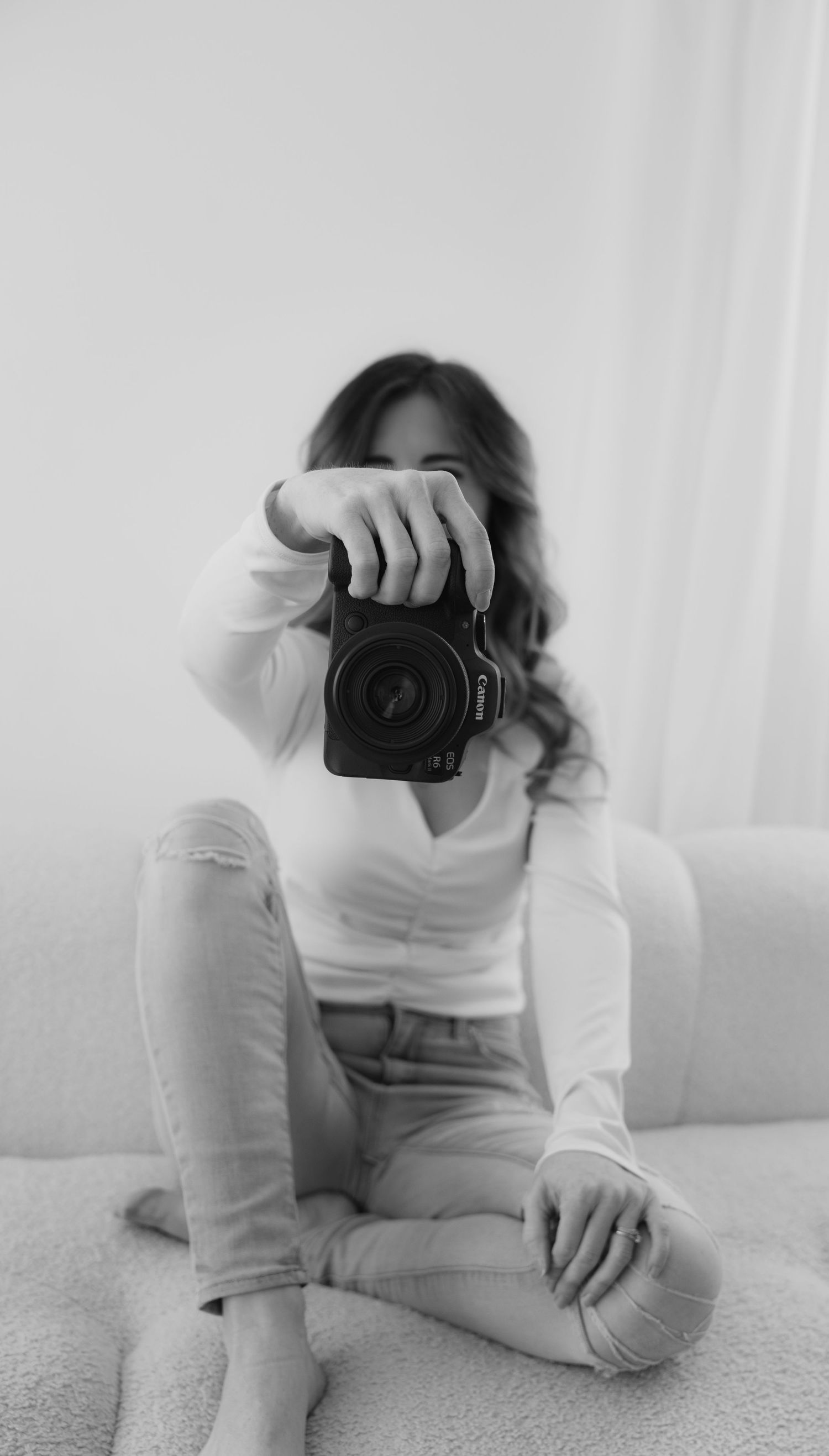 Black and white photo series of a Woodbury photographer sitting on the floor with a camera held out in front of them.