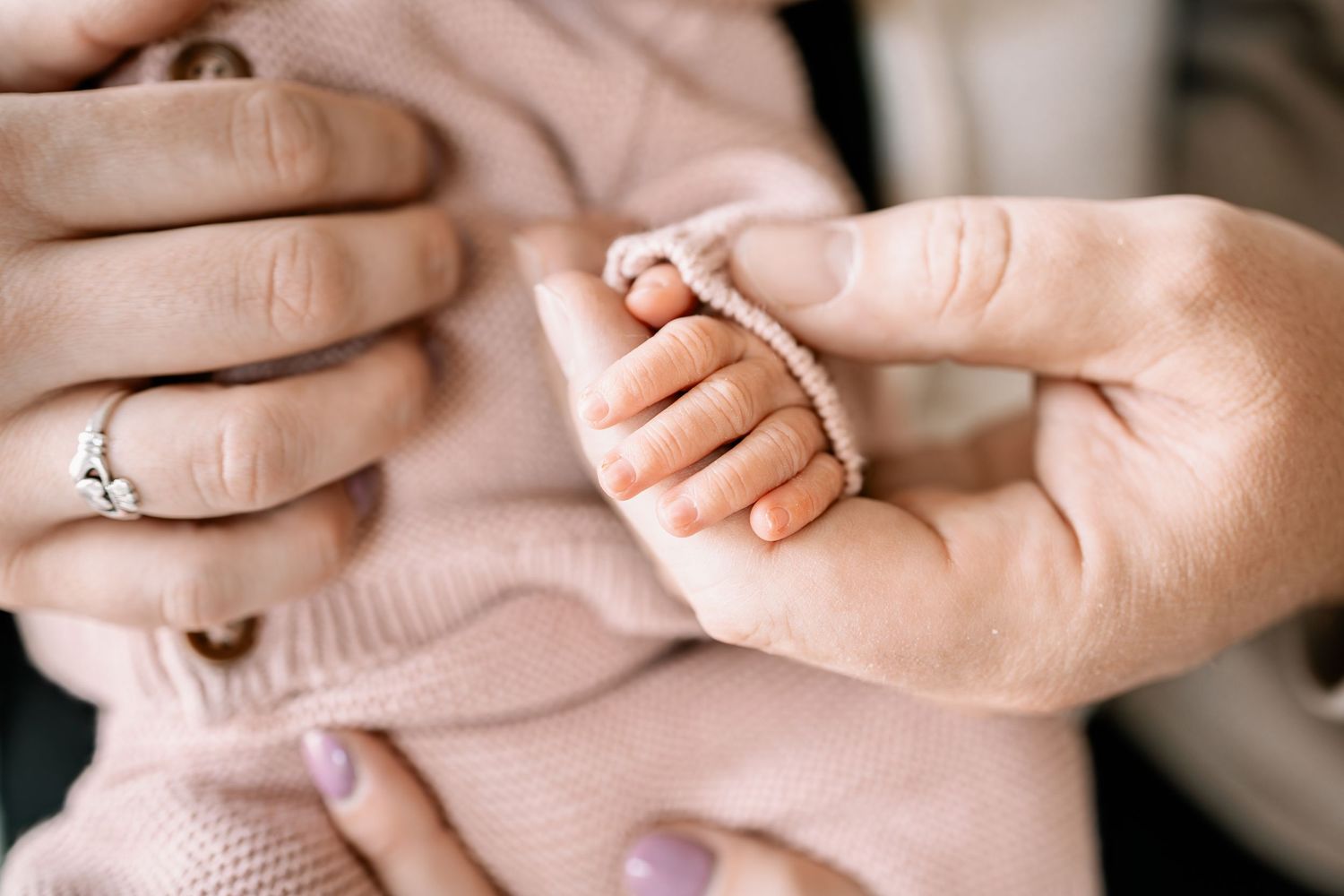 A newborn baby grasping an adult finger during an in home lifestyle newborn session in Woodbury, MN.