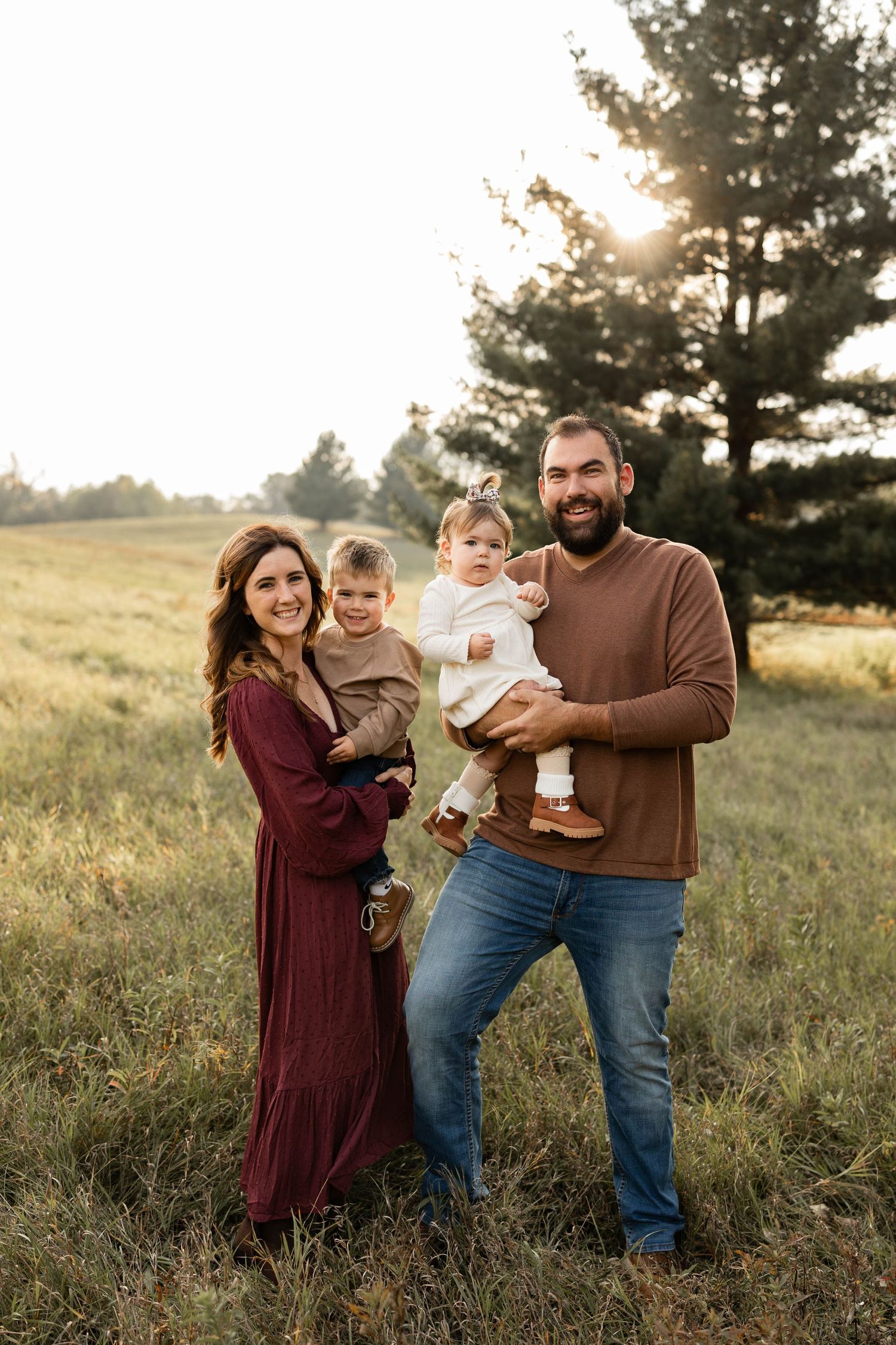 Woodbury photographer's family shares joyful moments together in a sun-drenched field during golden hour portrait session.