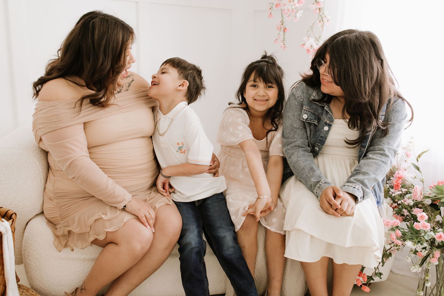 Mother and her children laughing together in a bright, floral studio during a family photo session in Lakeville