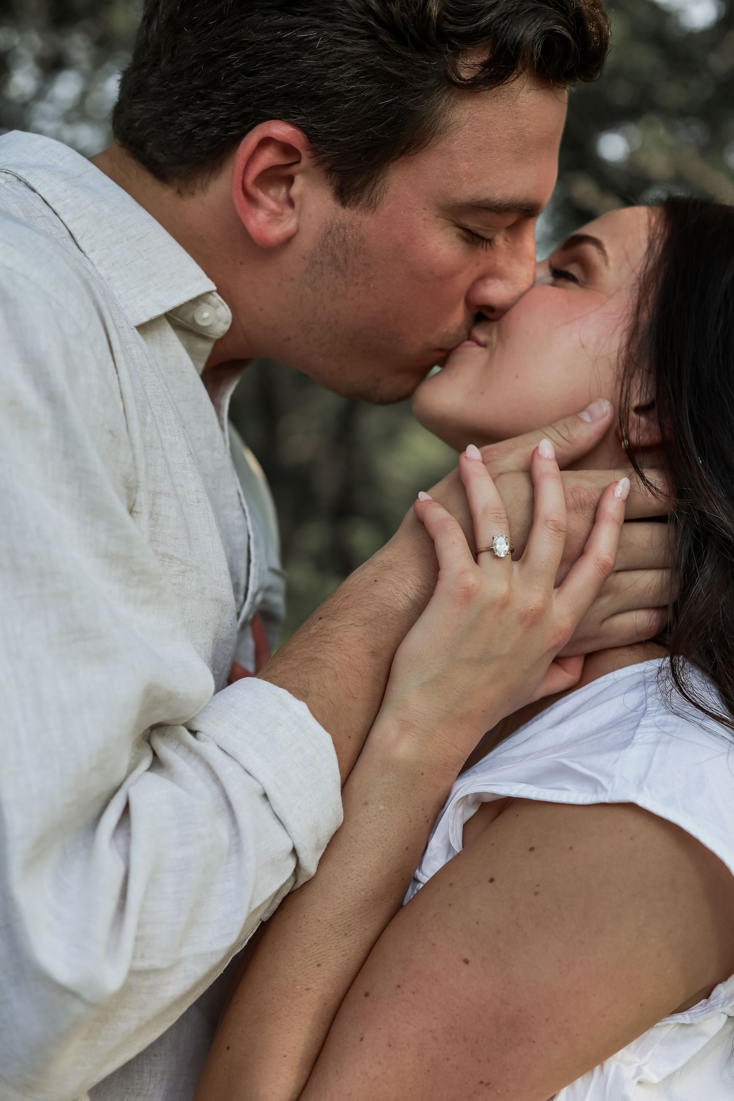 A romantic couple shares a tender kiss outdoors while displaying an engagement ring on her finger during Woodbury engagement photo session.
