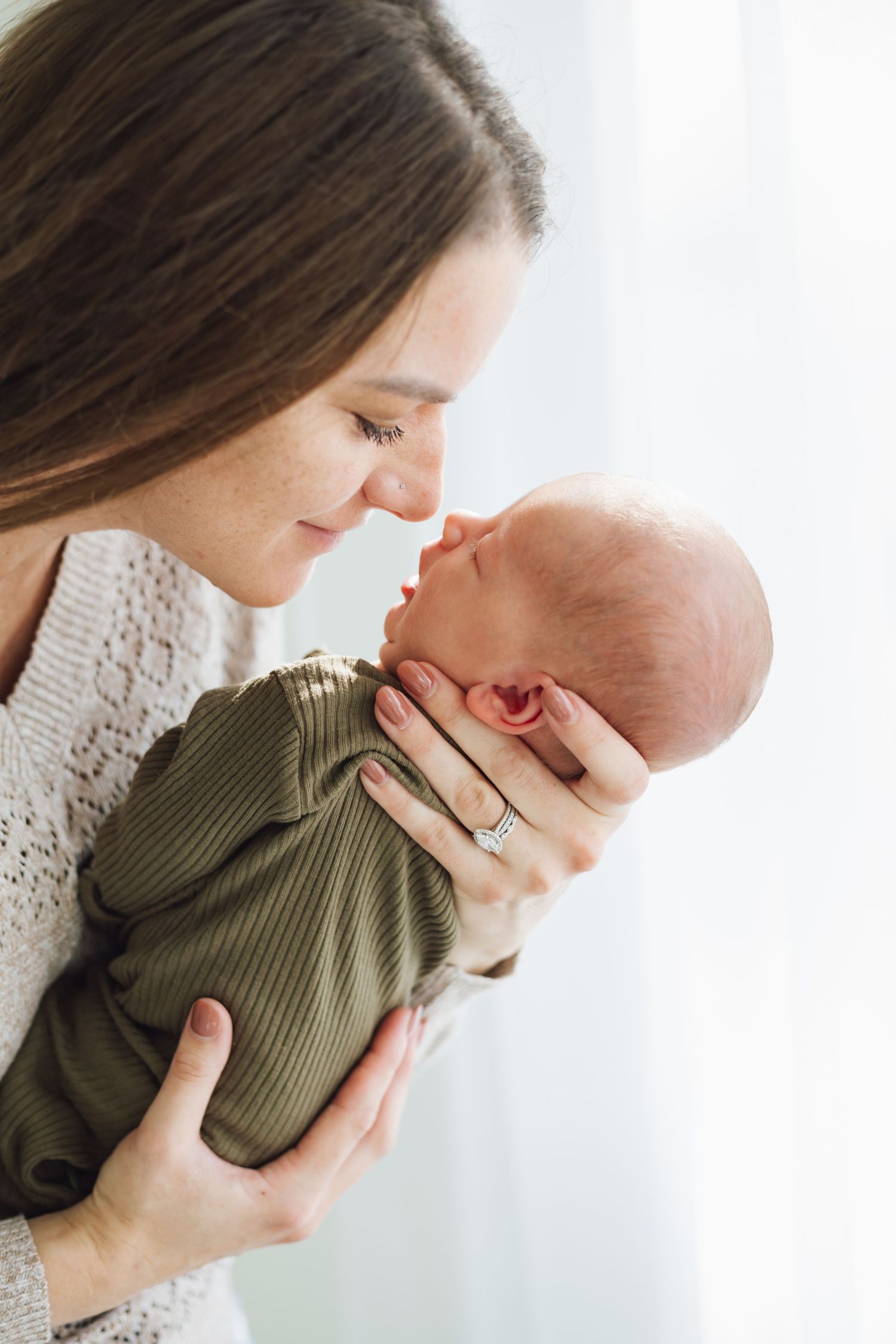 A tender moment between mother and newborn baby in soft natural light, captured by Woodbury newborn photographer.