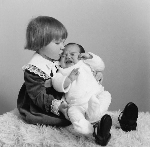 Family photograph of toddler and newborn sat posing for picture