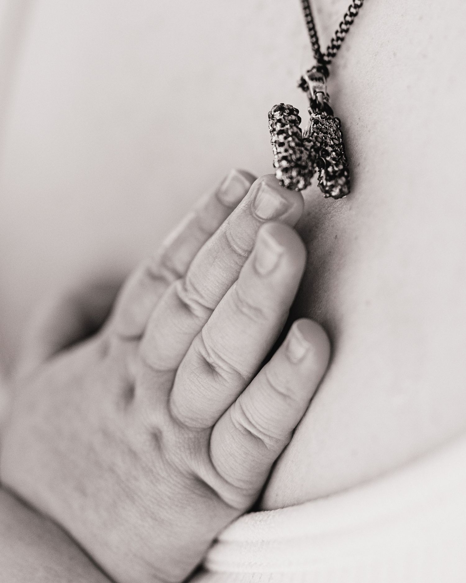 6 month old baby girls tiny hand plays with mums necklace during her milestone session in Ayrshire photography studio