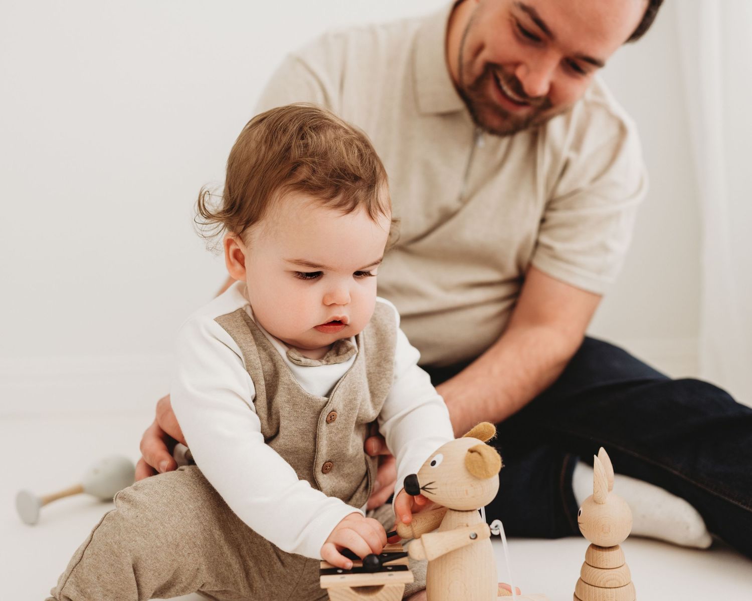 innocent 1 year old plays with a wooden toy during his milestone photoshoot in Ayrshire photography studio