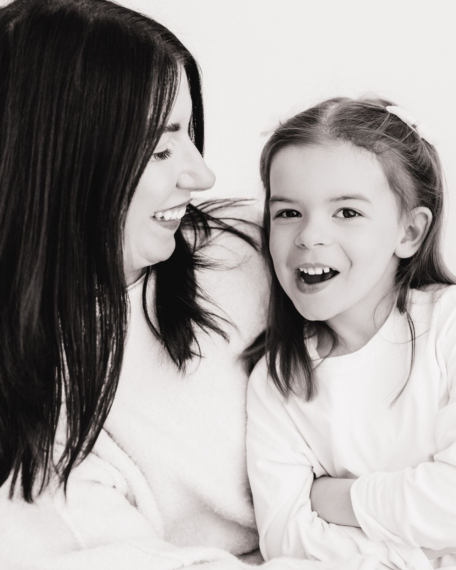 black and white photo of a mum gazing lovingly at her 5 year old daughter who smiles at the camera