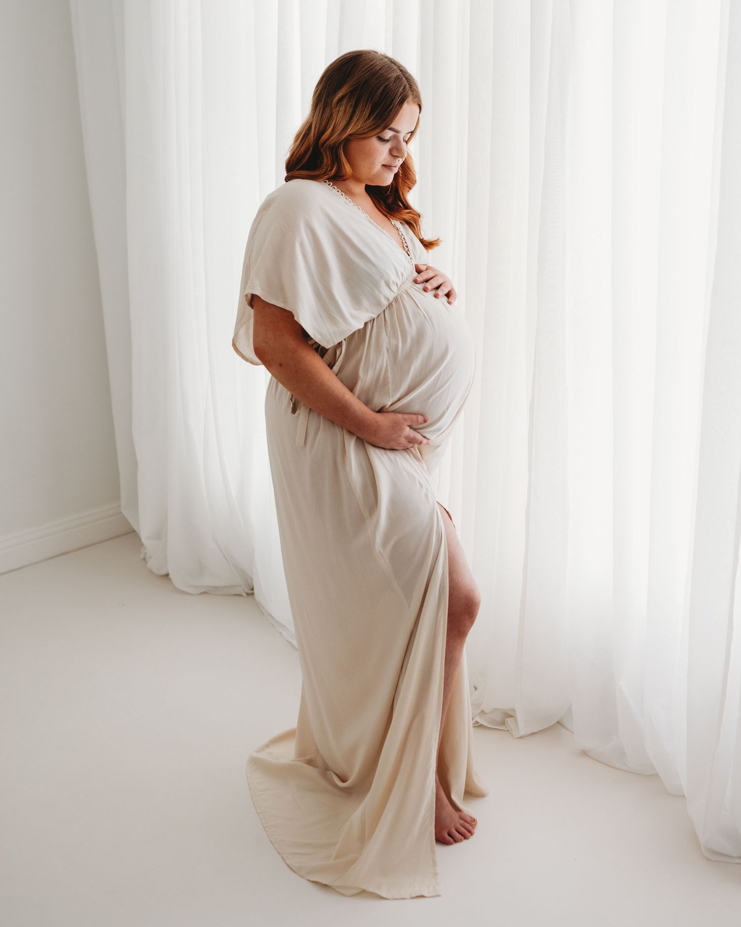 stunning elegant first time mum wears a white gown during her maternity session creating an ethereal look that captures her love &strength