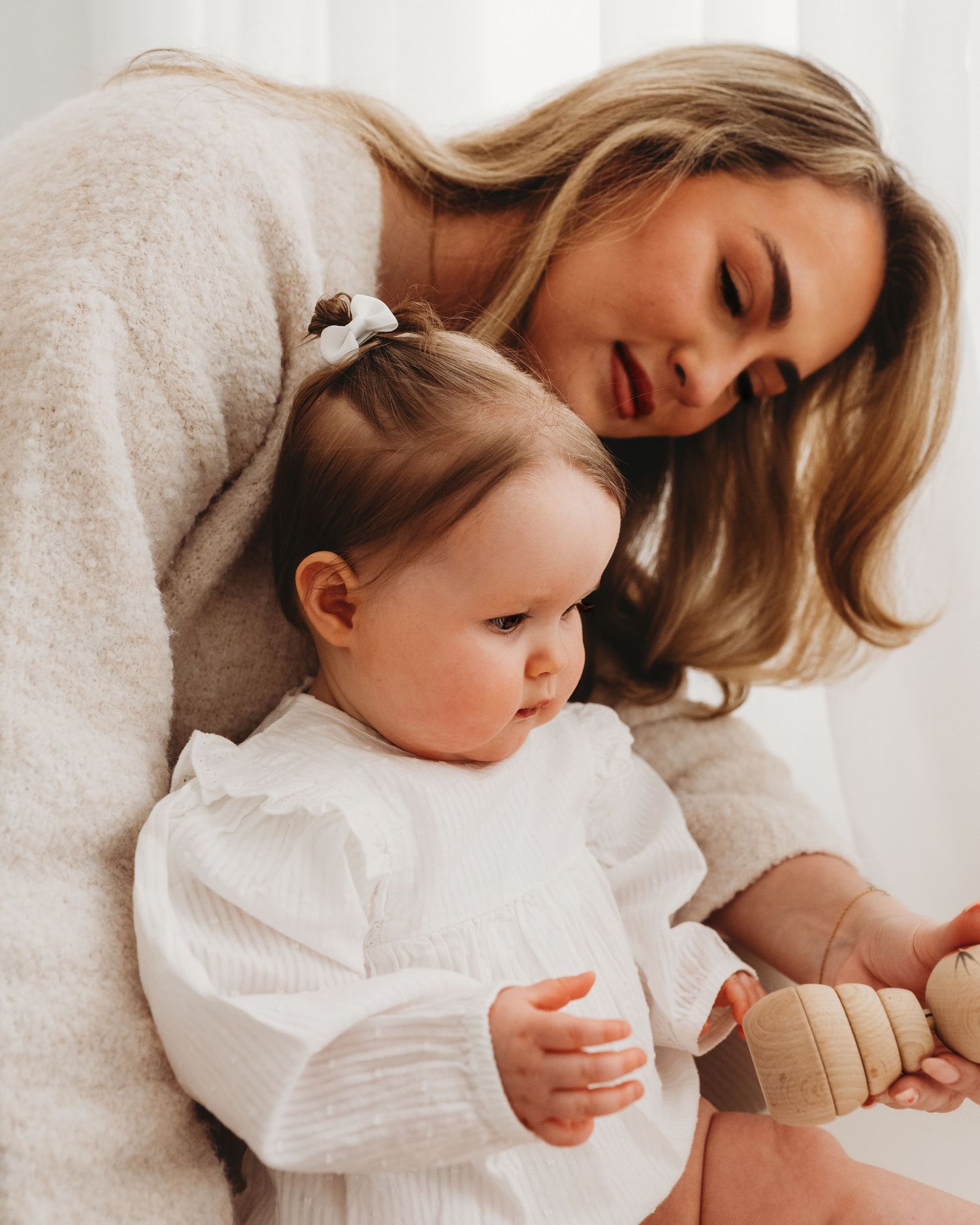 natural, playful moment captured between a first time mum and her almost 1 year old daughter as they play with wooden toys