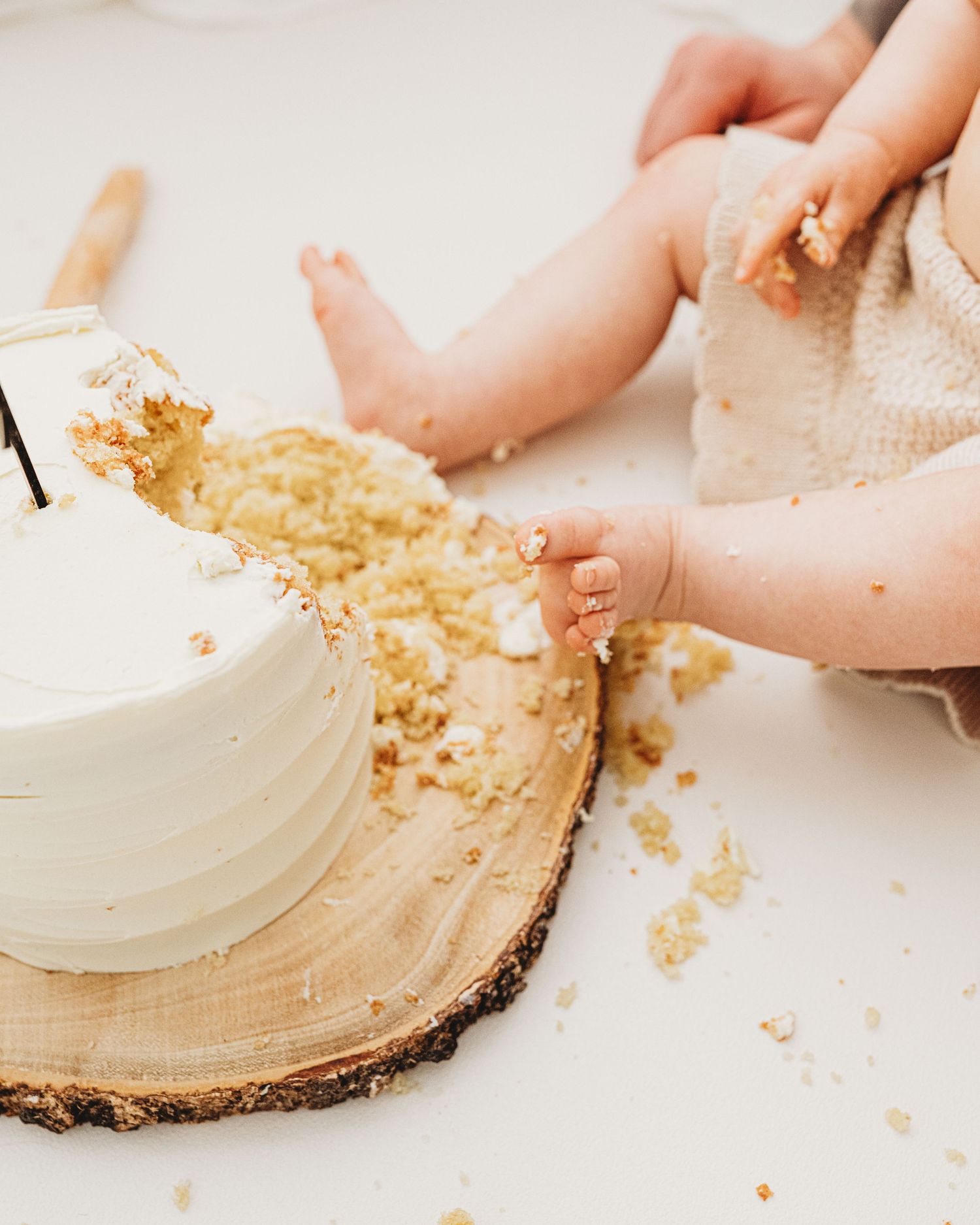 In a minimalist all-white Ayrshire studio, baby's 1st birthday is captured timelessly, her feet smashing her cake