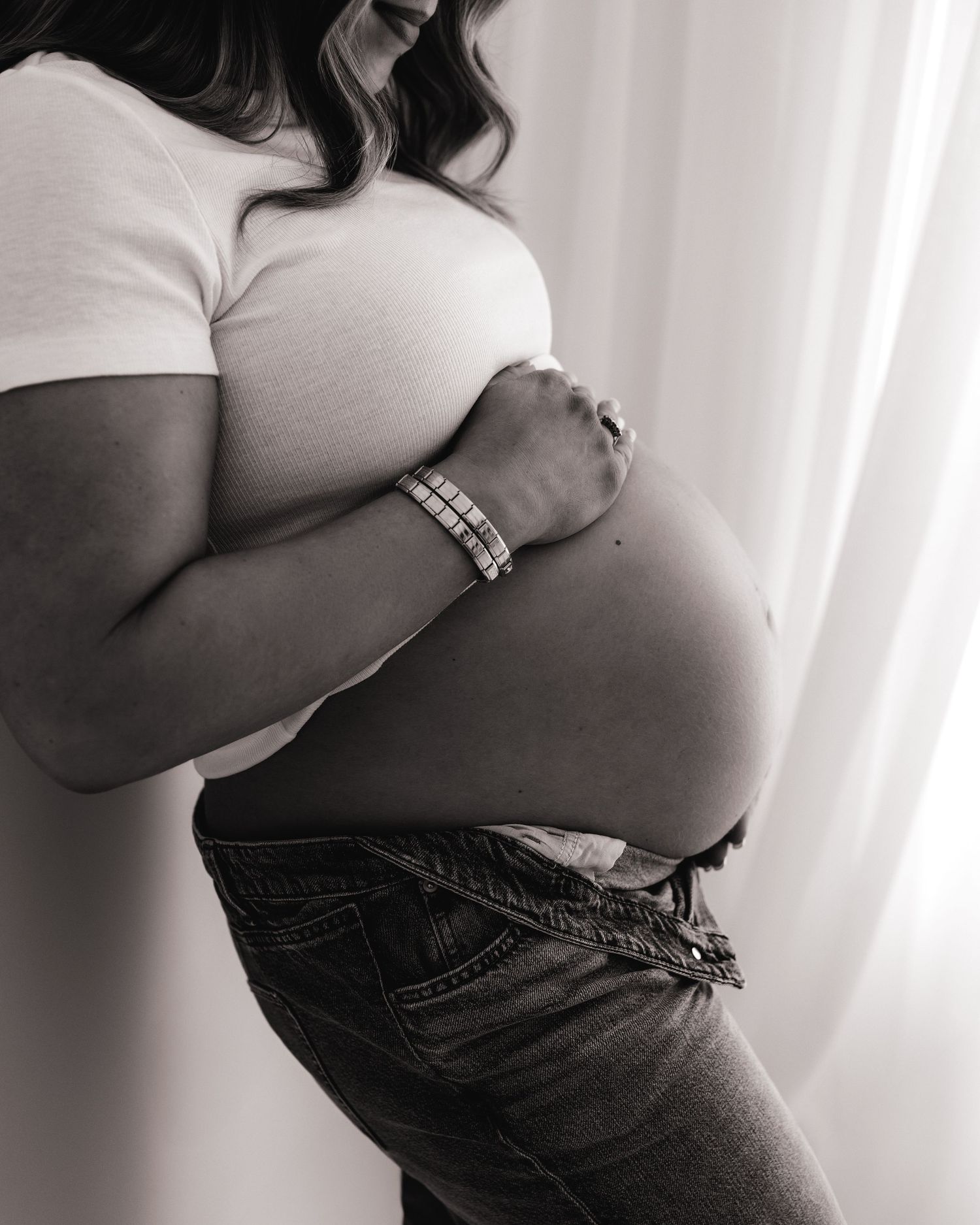 black and white modern maternity portrait of first time mum cradling her bump with her hands