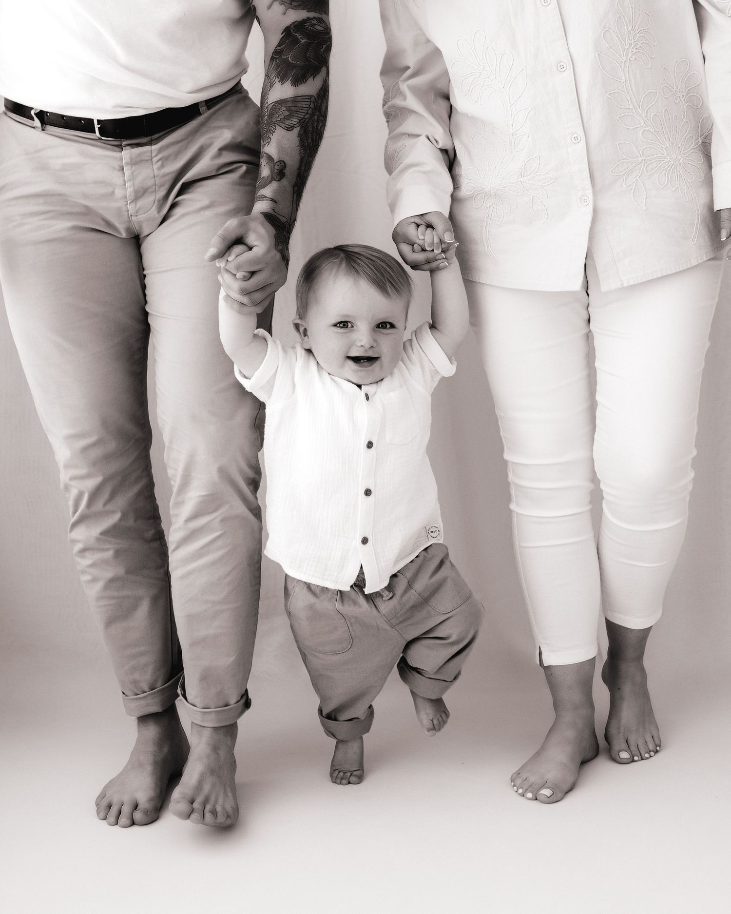 black and white photo of baby's first steps, protected by his loving parents