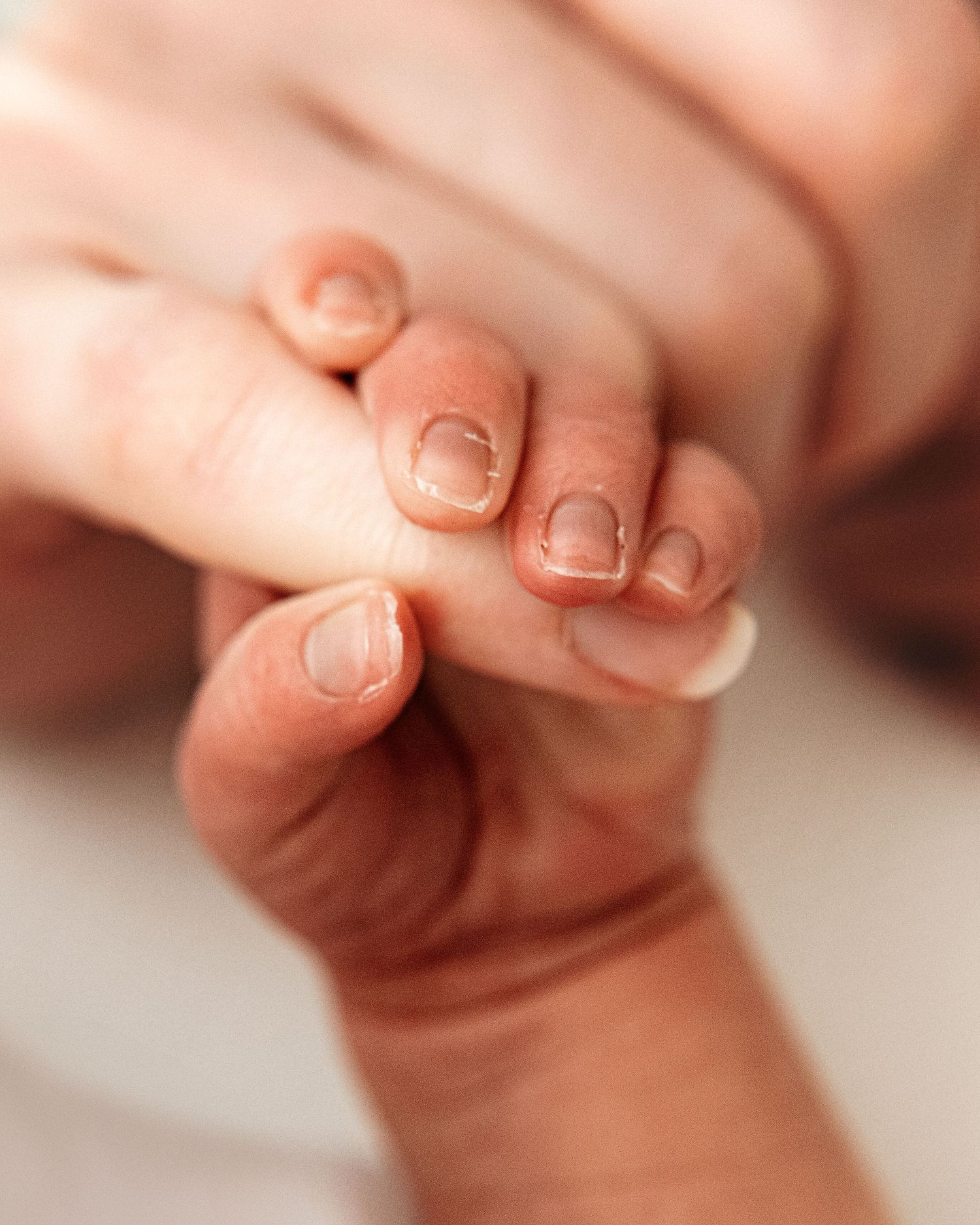 Ayrshire newborn baby tightly grips his mums's finger during his natural newborn photoshoot, his tiny size clearly evident