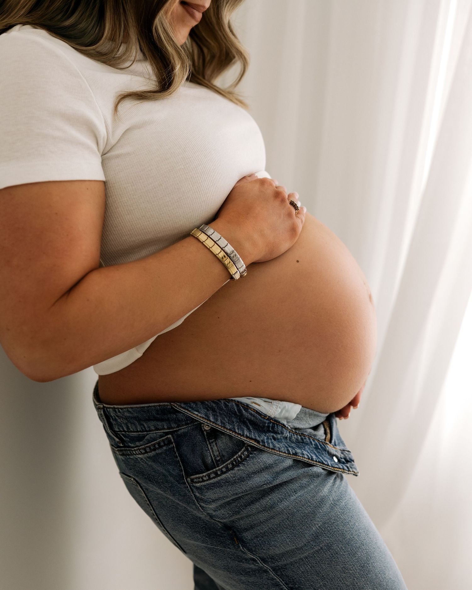 a modern mother wearing blue jeans & a white t-shirt has a natural maternity portrait captured in Ayrshire studio