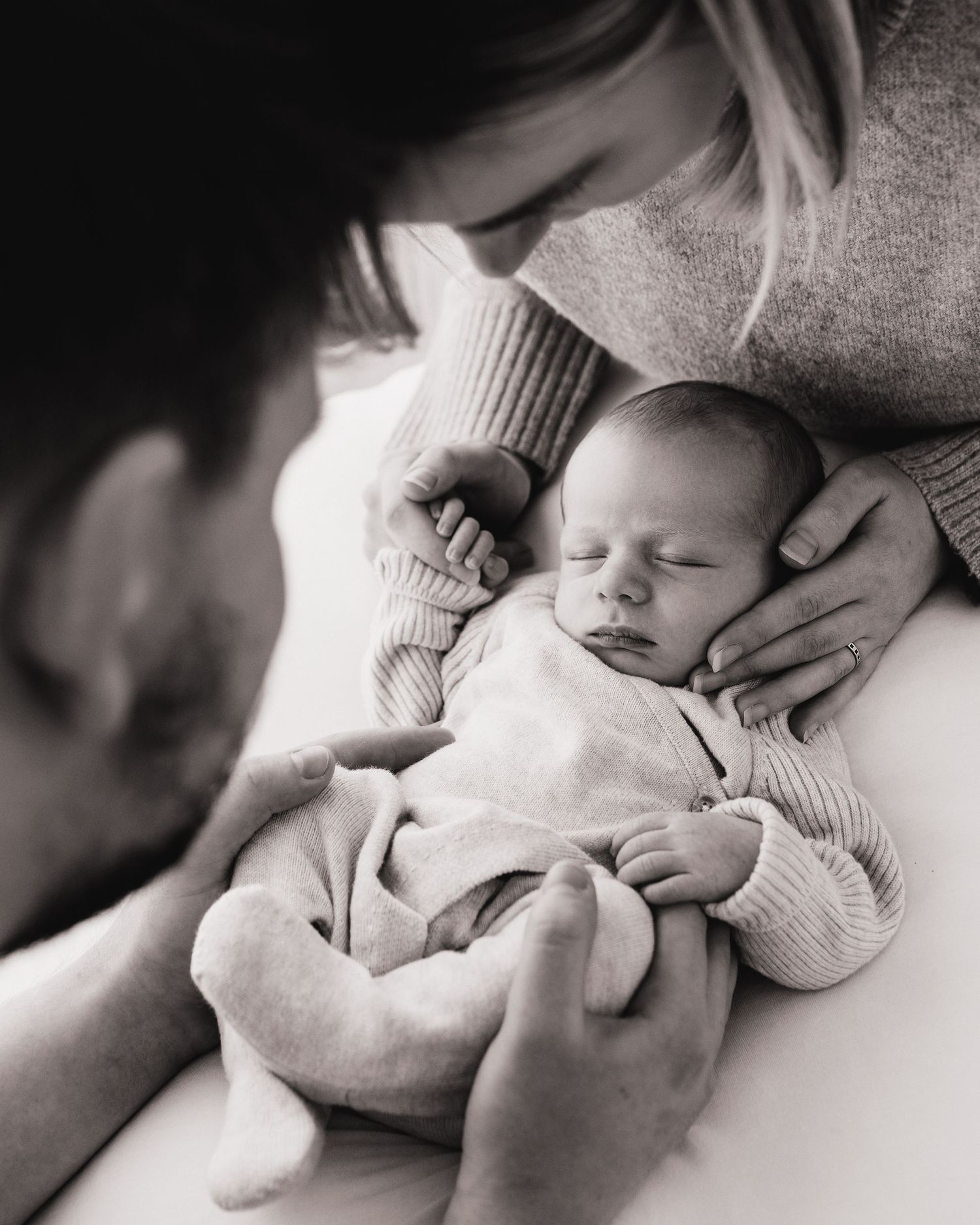 first time parents surrounded their new son with their hands & love, gazing down at him during a quiet moment in Ayrshire newborn photoshoot