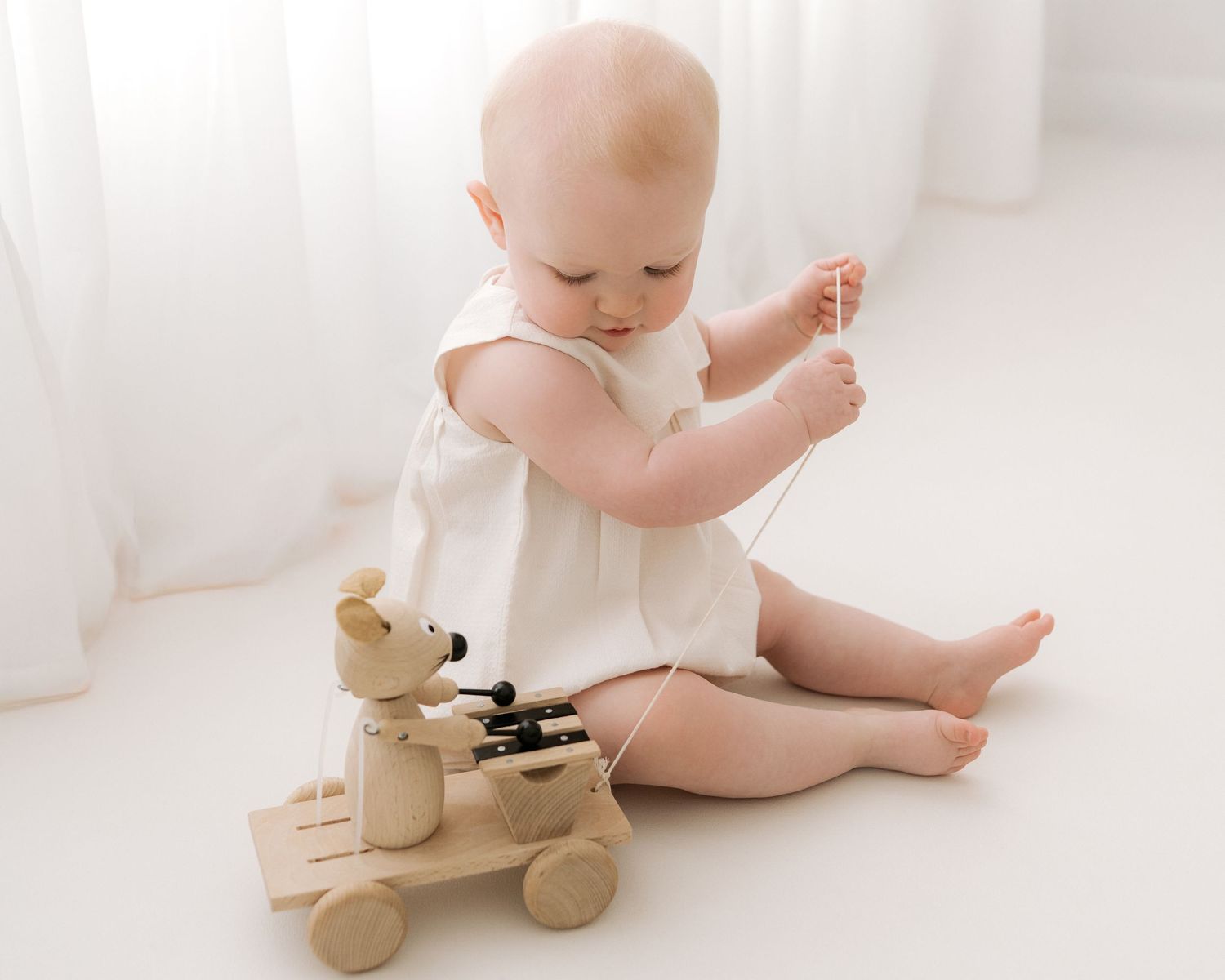 playing with a wooden pull along toy, curious 1 year old celebrates her 1st birthday in Ayrshire photography studio