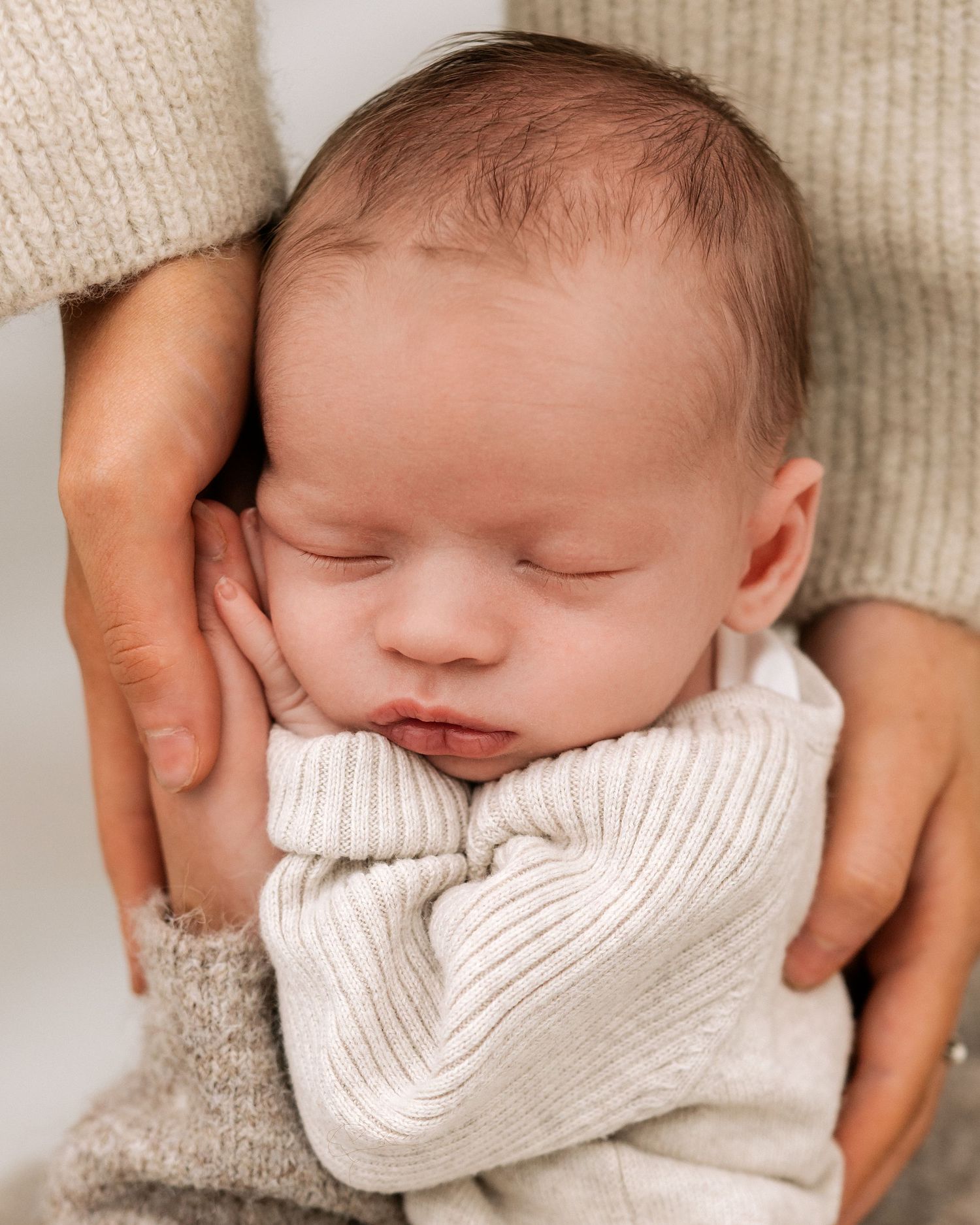 2 week old Ayrshire newborn baby sleeps on his mum and aunts hands during his natural newborn photoshoot